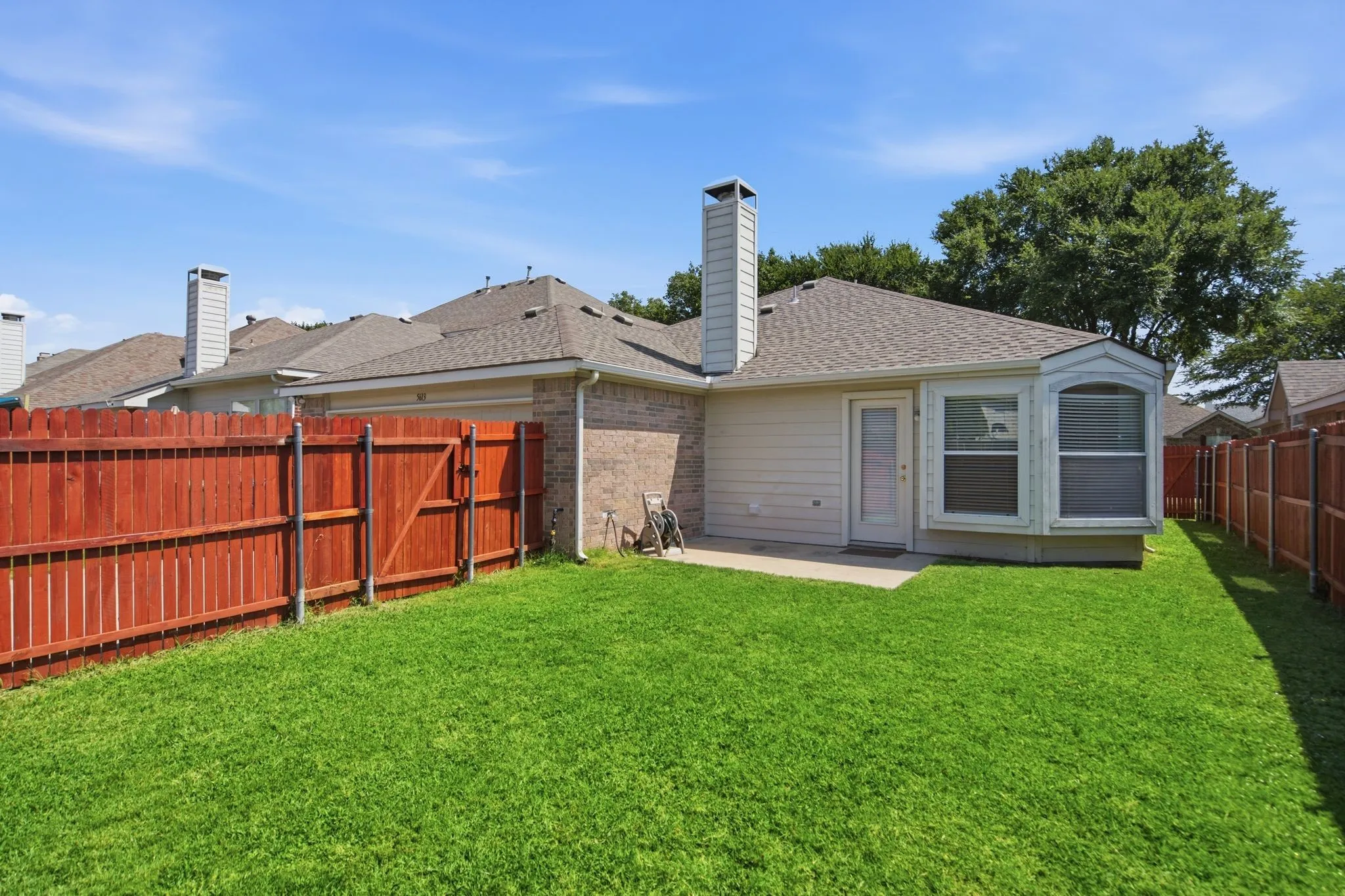 Expansive backyard featuring a lush lawn and a wood privacy fence with a gate