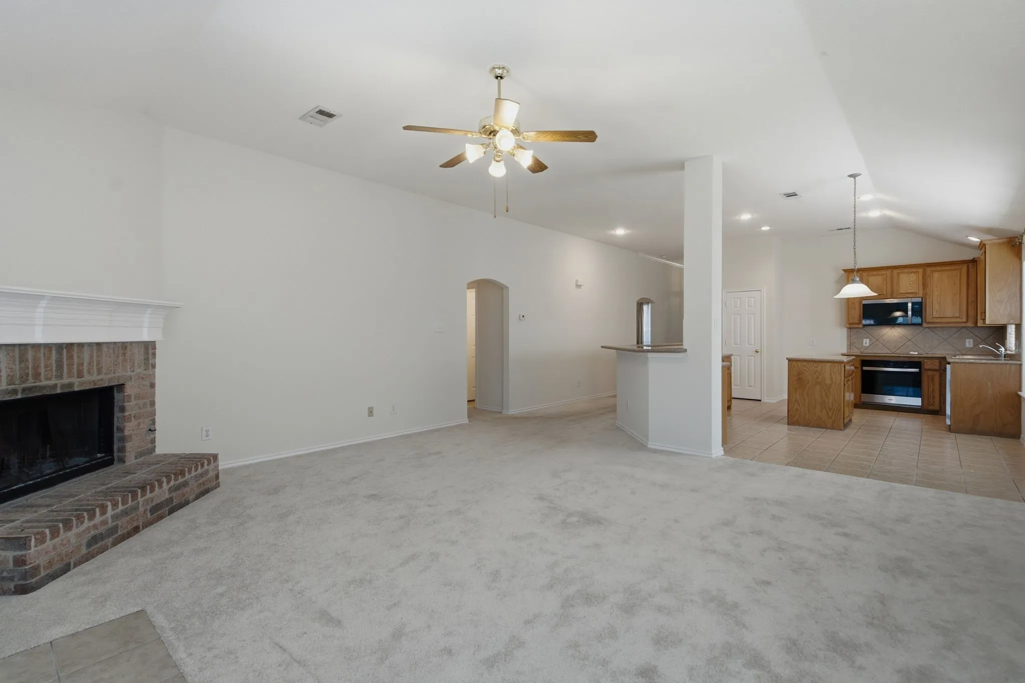 Living area with brick fireplace, vaulted ceiling, and recessed lighting