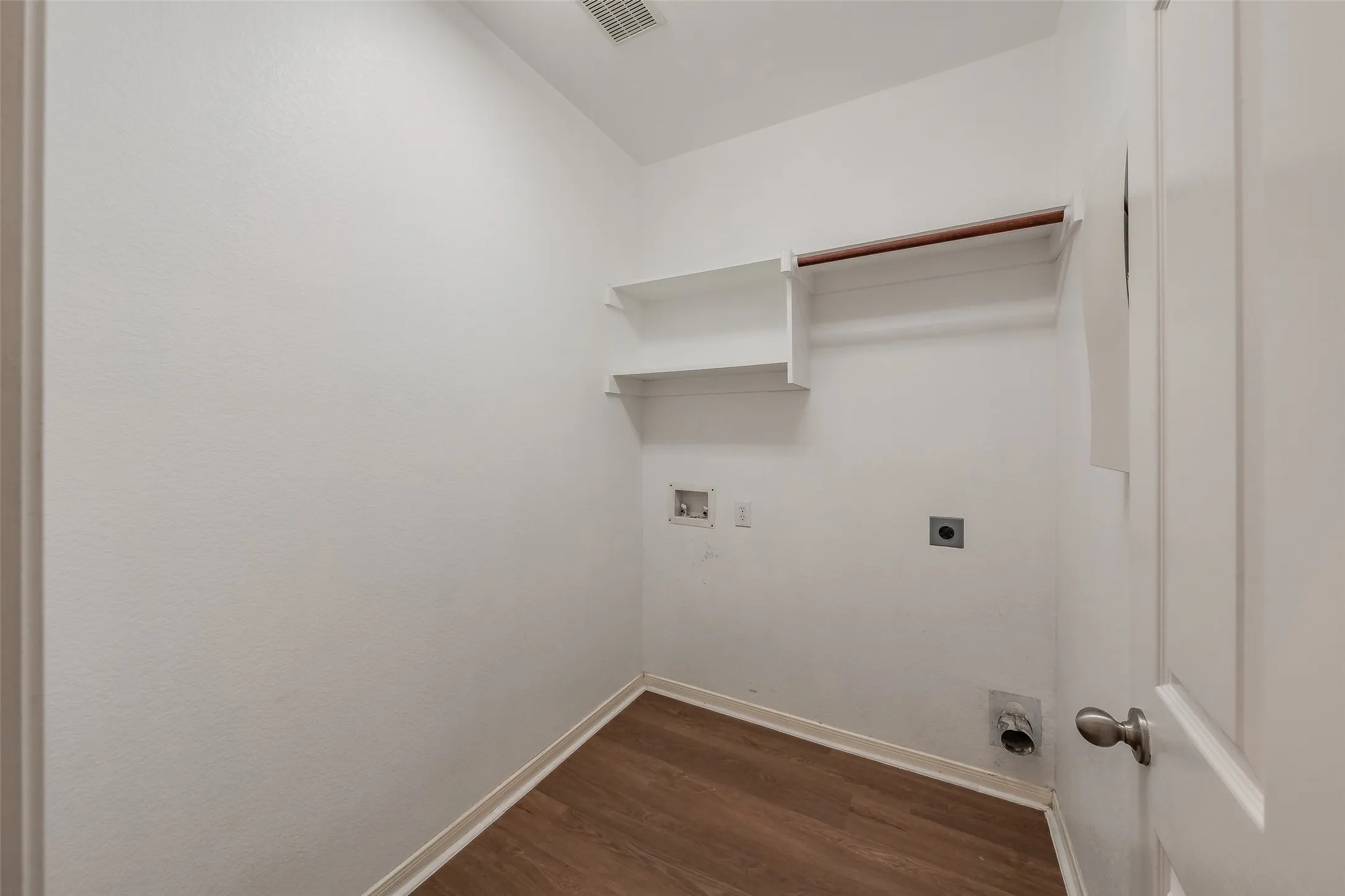 Separate utility room with washer and dryer connections, storage shelves and space for laundry organization.