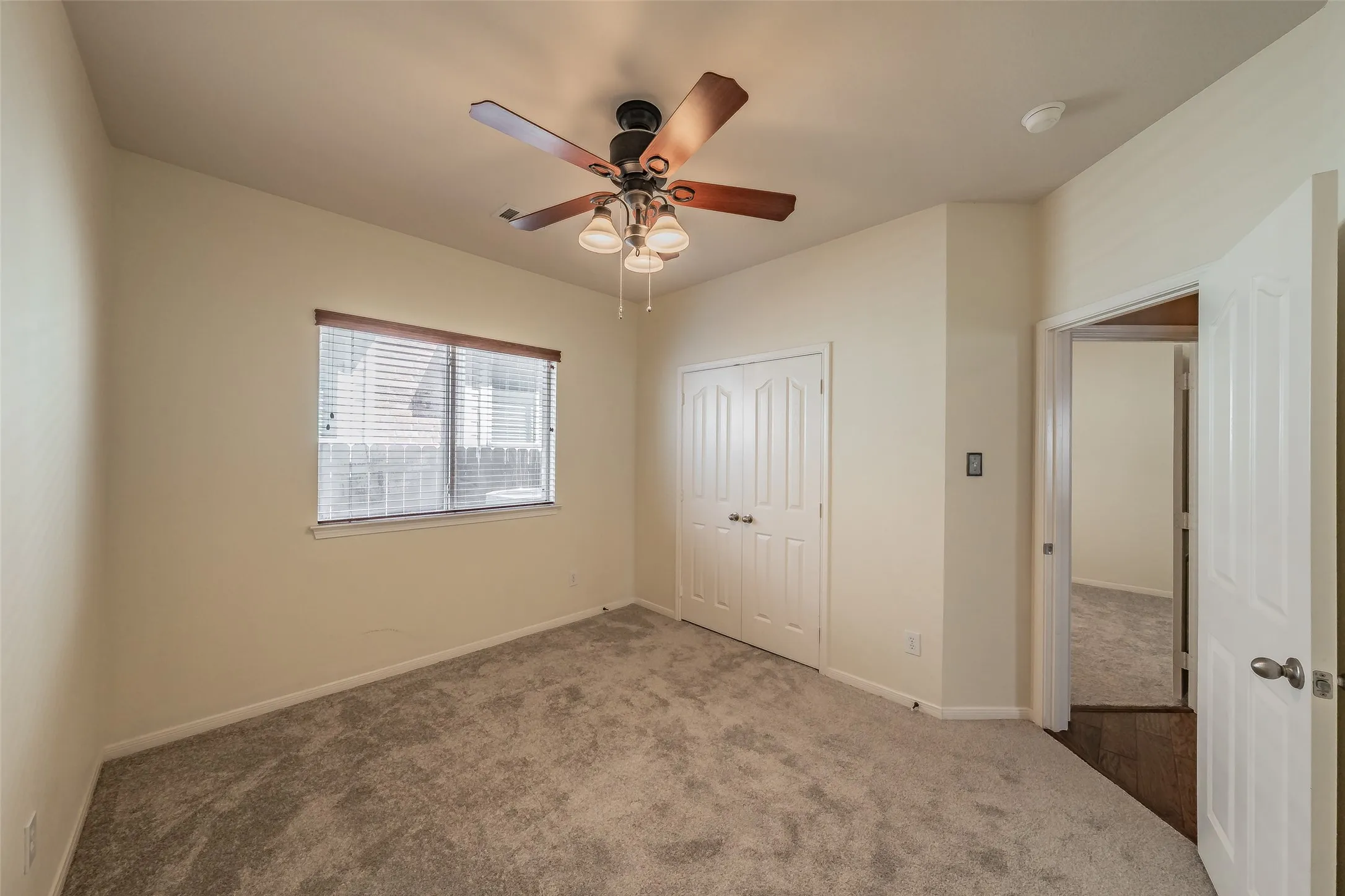 Comfortable secondary bedroom with fresh carpet, ceiling fan and double-door closet.