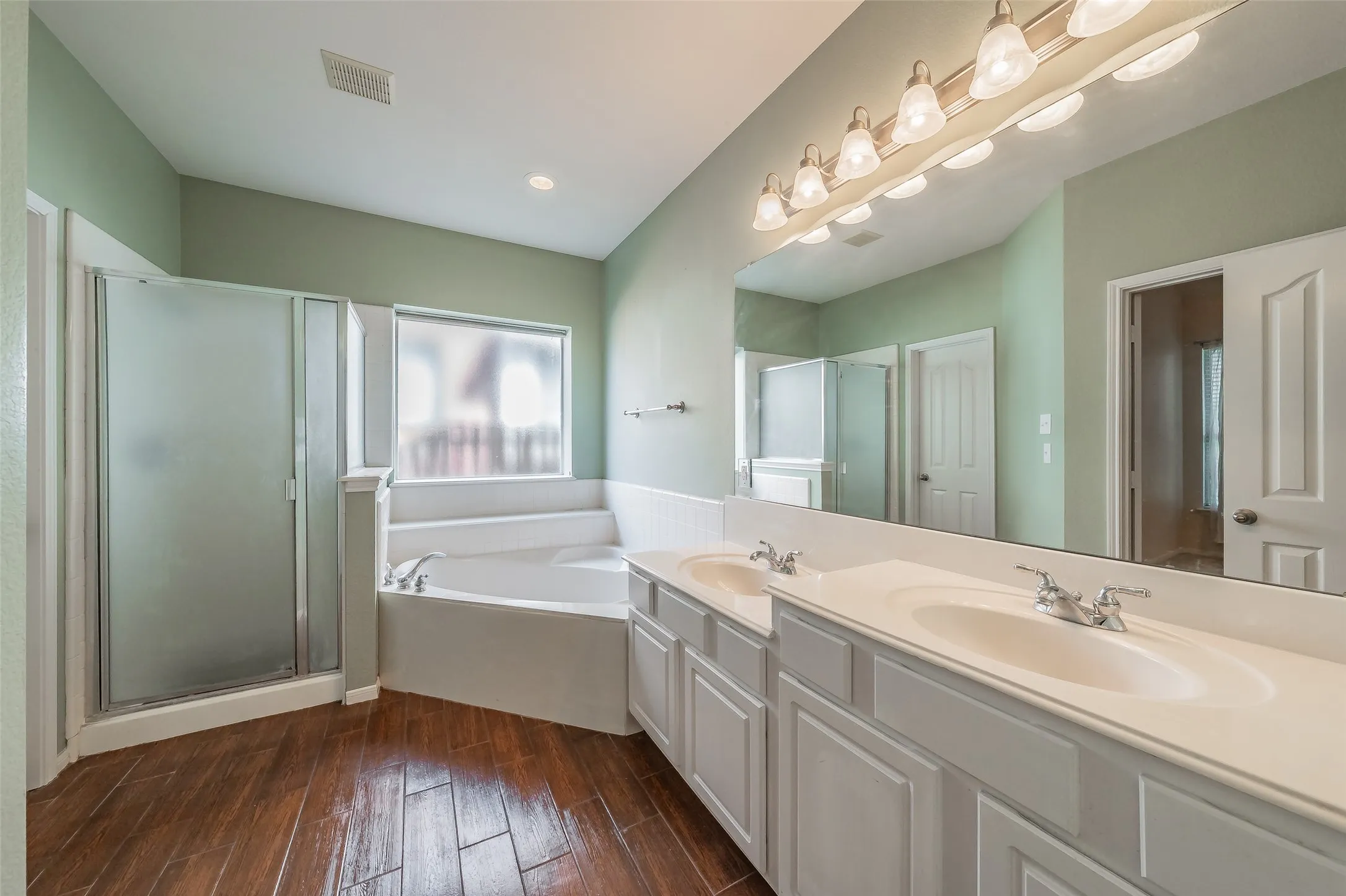 Primary bathroom with dual sinks, soaking tub, separate shower and an oversized vanity.