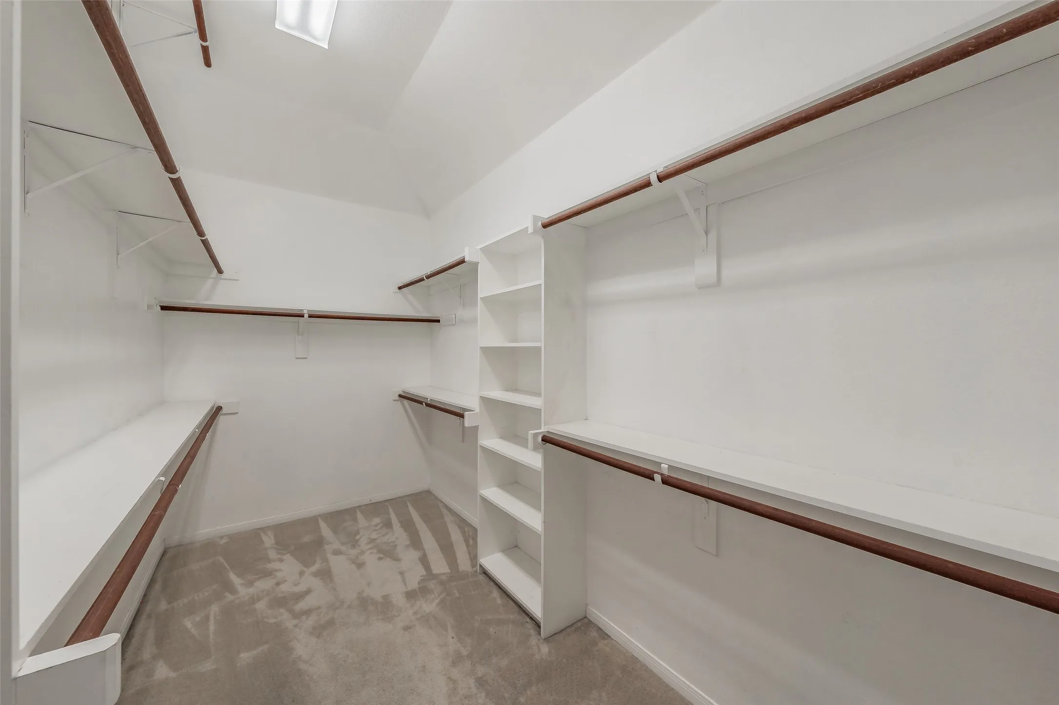 Large walk-in primary closet with extensive hanging space, shelving and built-in storage.