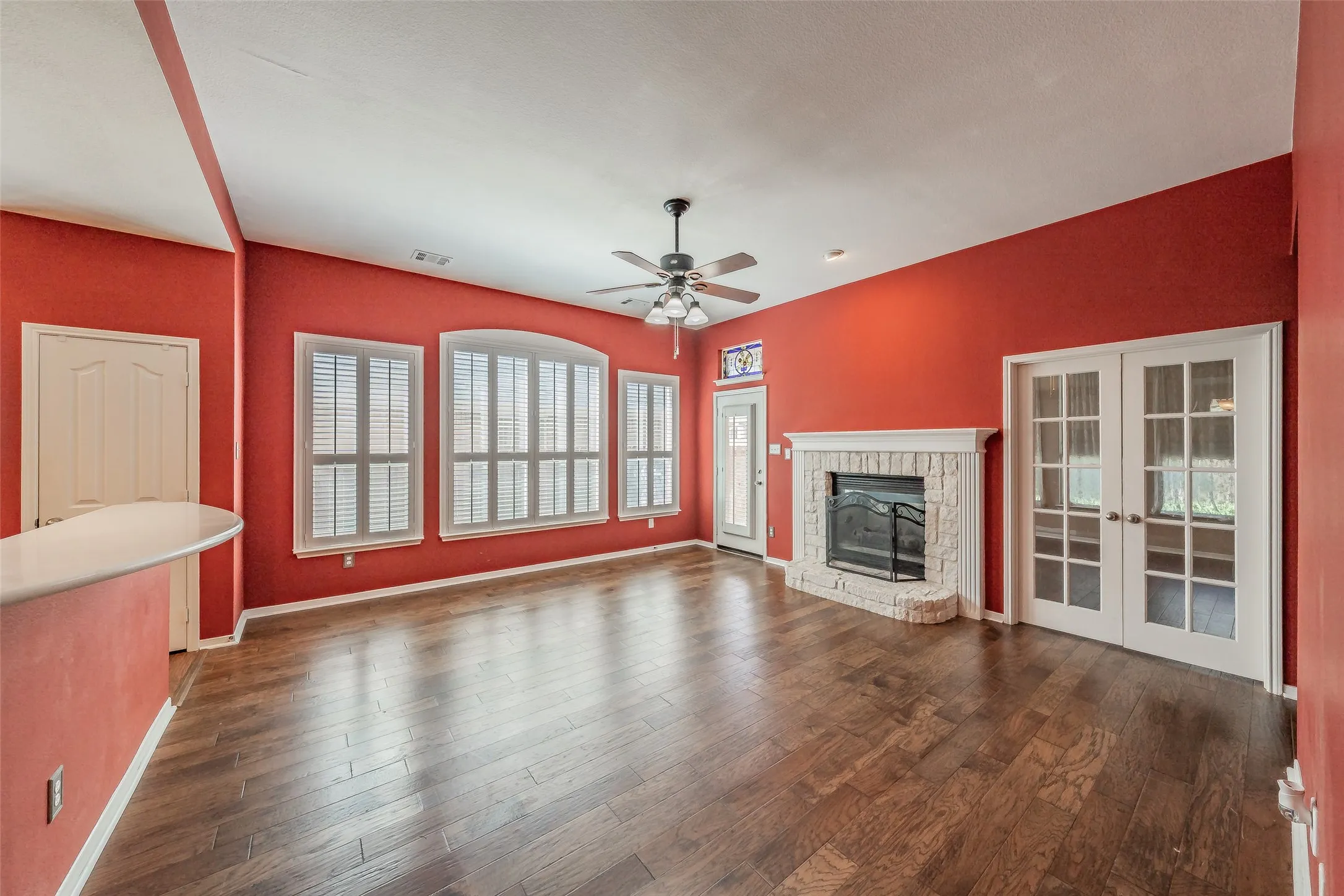 Bright Fort Worth living space with a wall of windows, fireplace and French doors leading to a flexible bonus room.