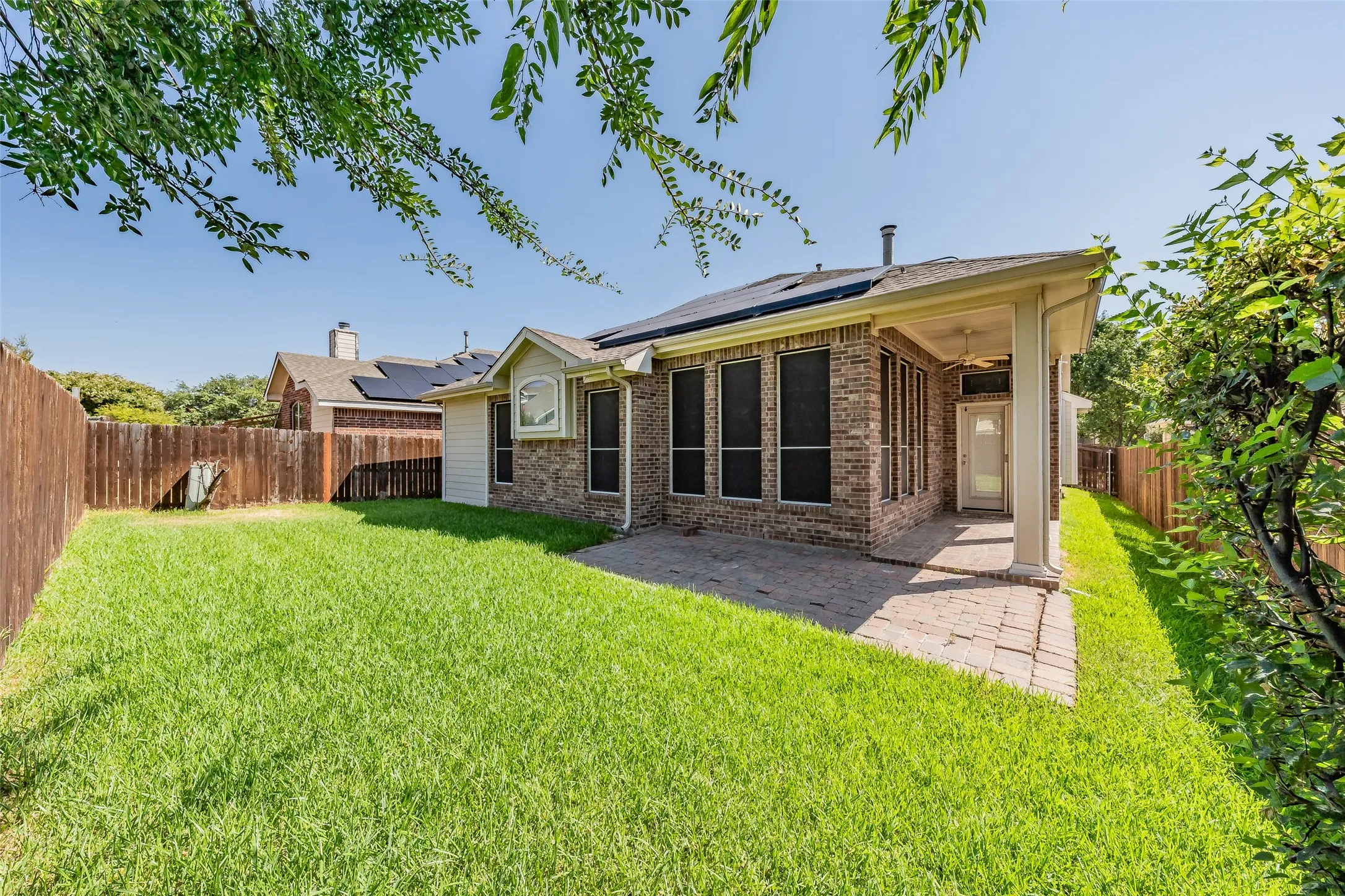 Fenced backyard with green lawn, mature landscaping and a covered patio for outdoor relaxation.