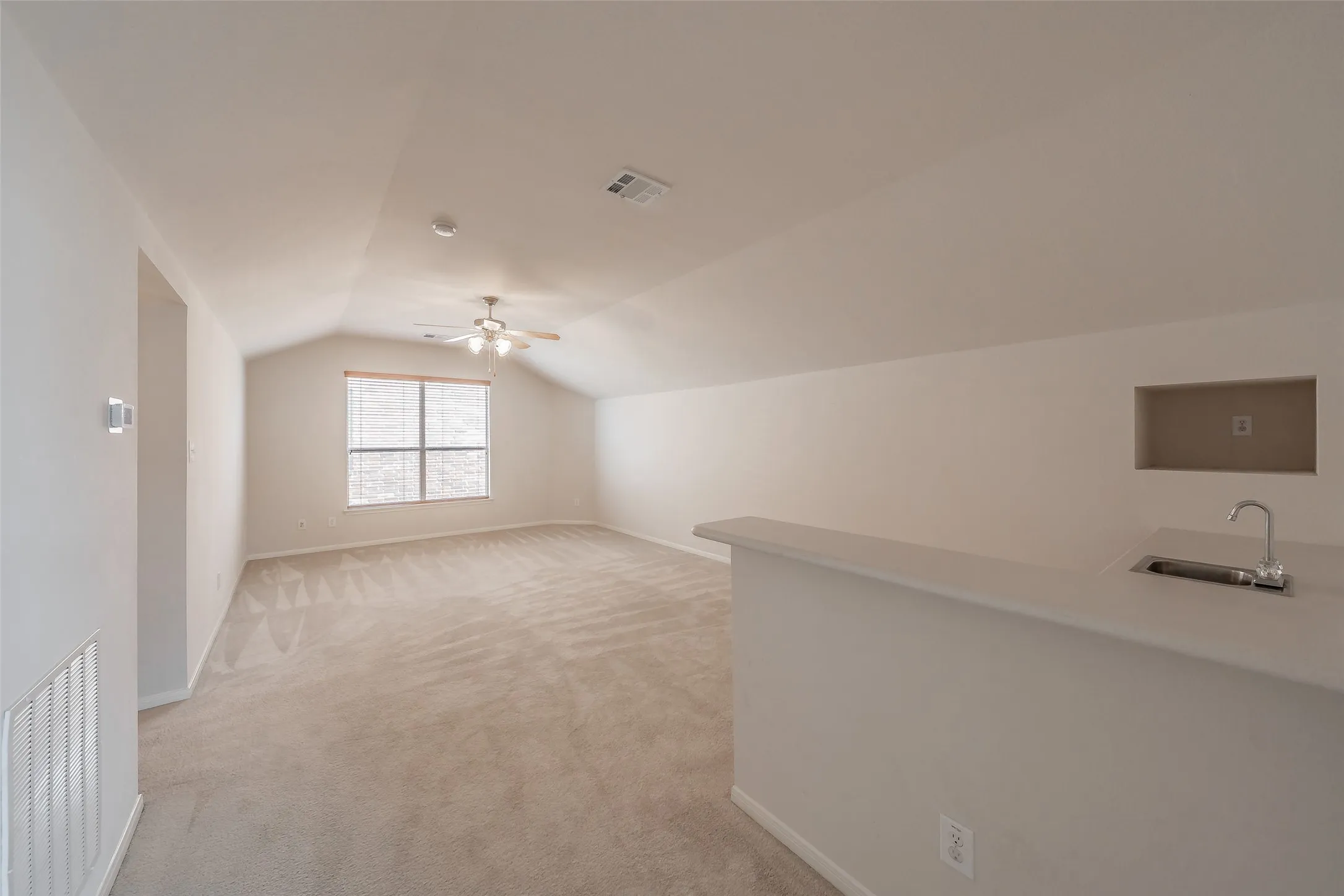 Upstairs game room or bonus room with vaulted ceiling, wet bar and space for multiple activity zones.