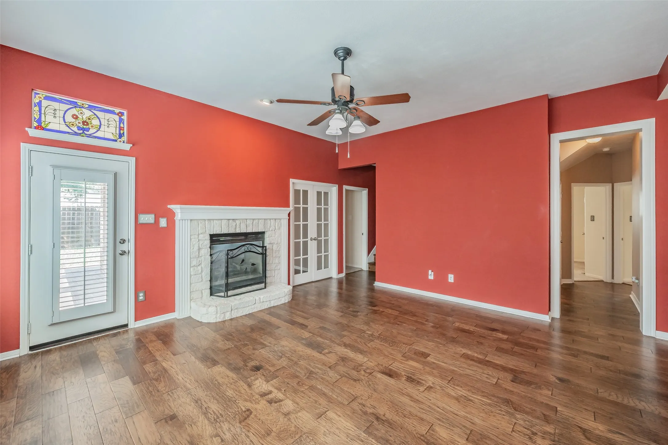 Main living area featuring wood flooring, a fireplace, ceiling fan and access to the backyard.
