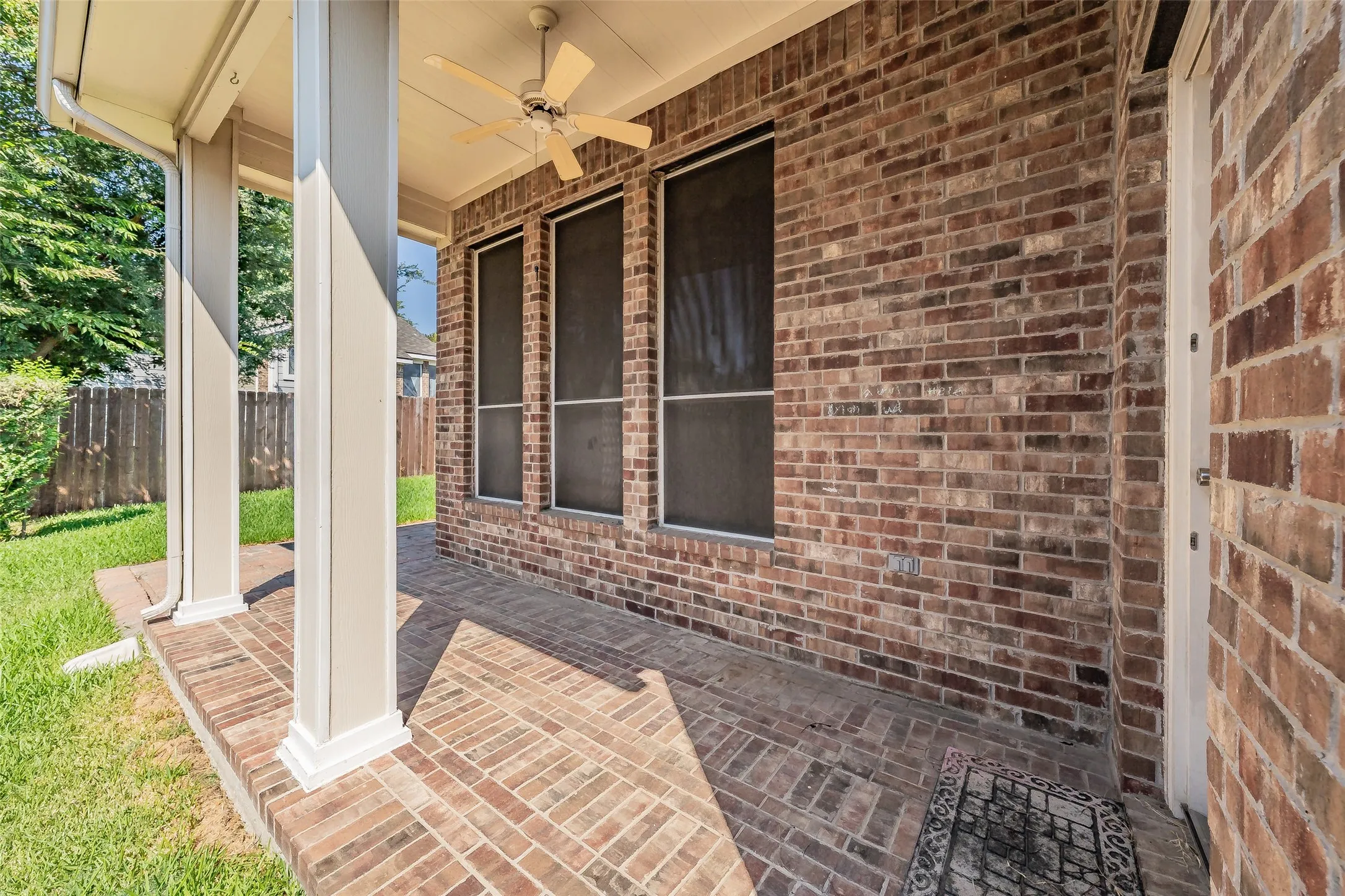 Covered brick patio with ceiling fan provides a comfortable extension of the home’s outdoor living space.