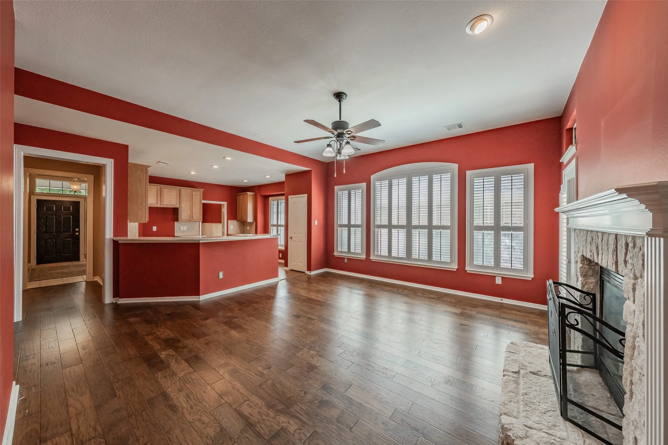 Expansive main living area with wood flooring, fireplace, abundant windows and an open connection to the kitchen.