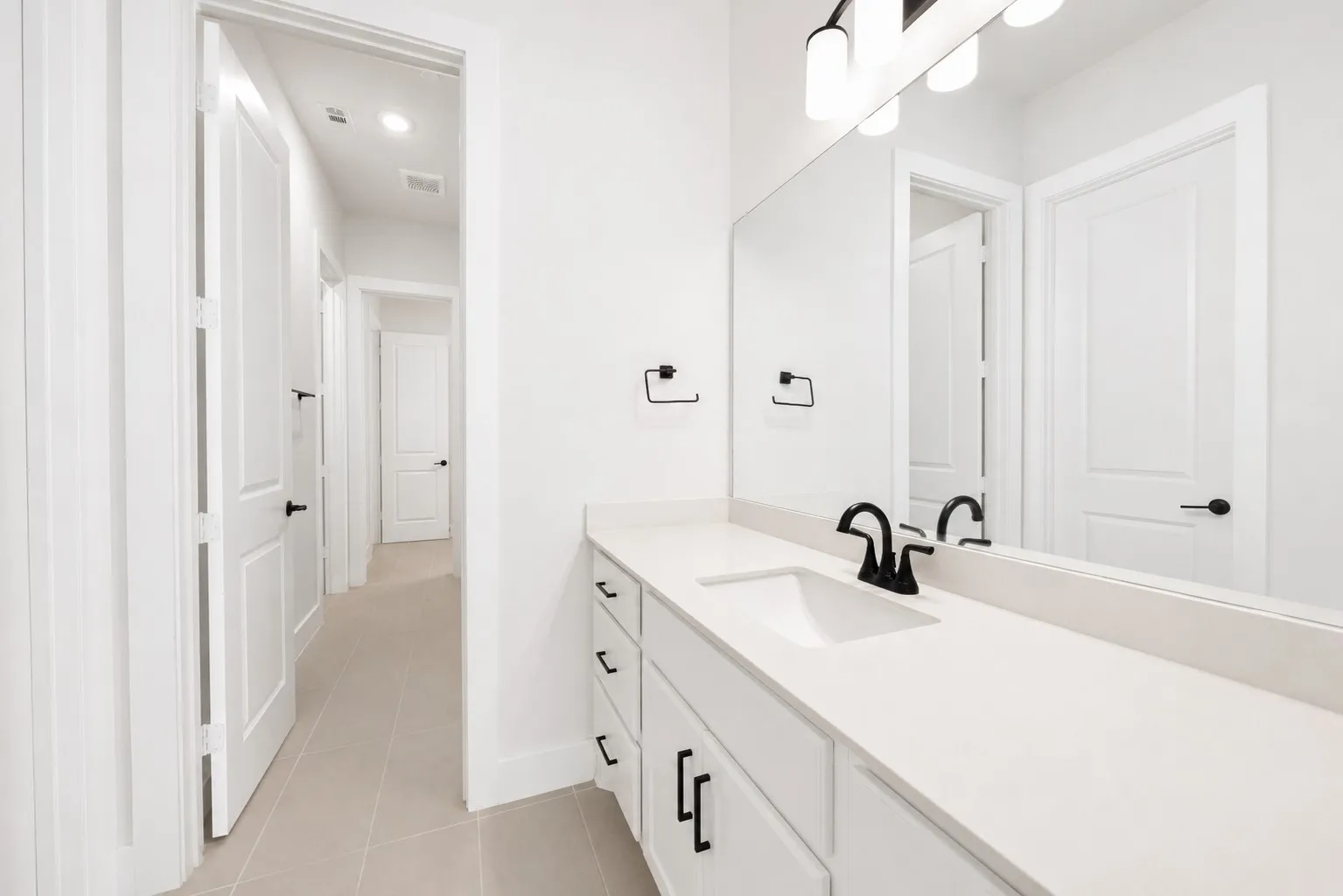 Bathroom vanity featuring a light-colored countertop, integrated sink, and matte black faucet