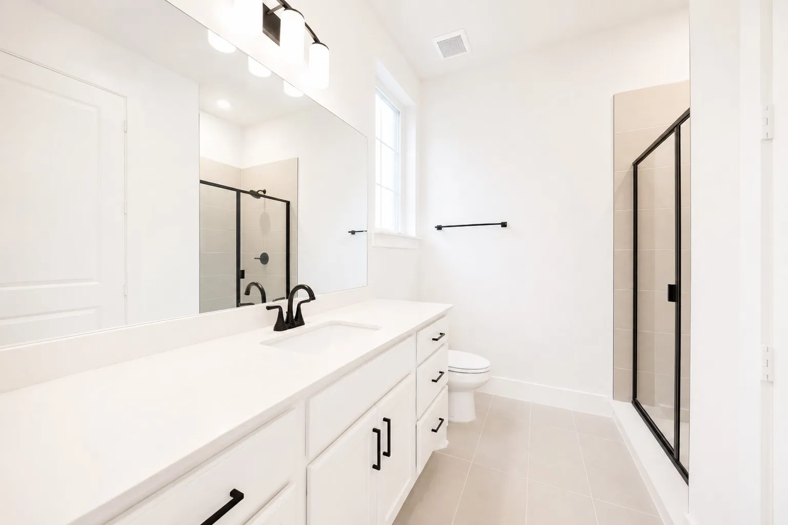 Contemporary bathroom featuring a spacious vanity with an undermount sink, white cabinetry, and matte black hardware