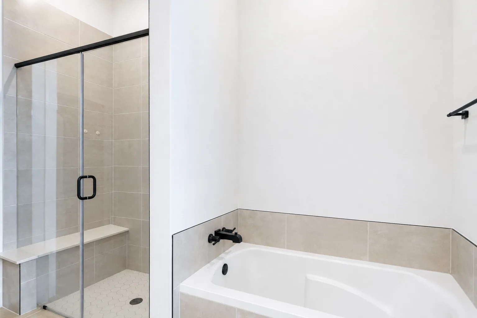 Bathroom featuring a built-in tub with matte black fixtures, a tiled surround, and a glass-enclosed shower with a bench