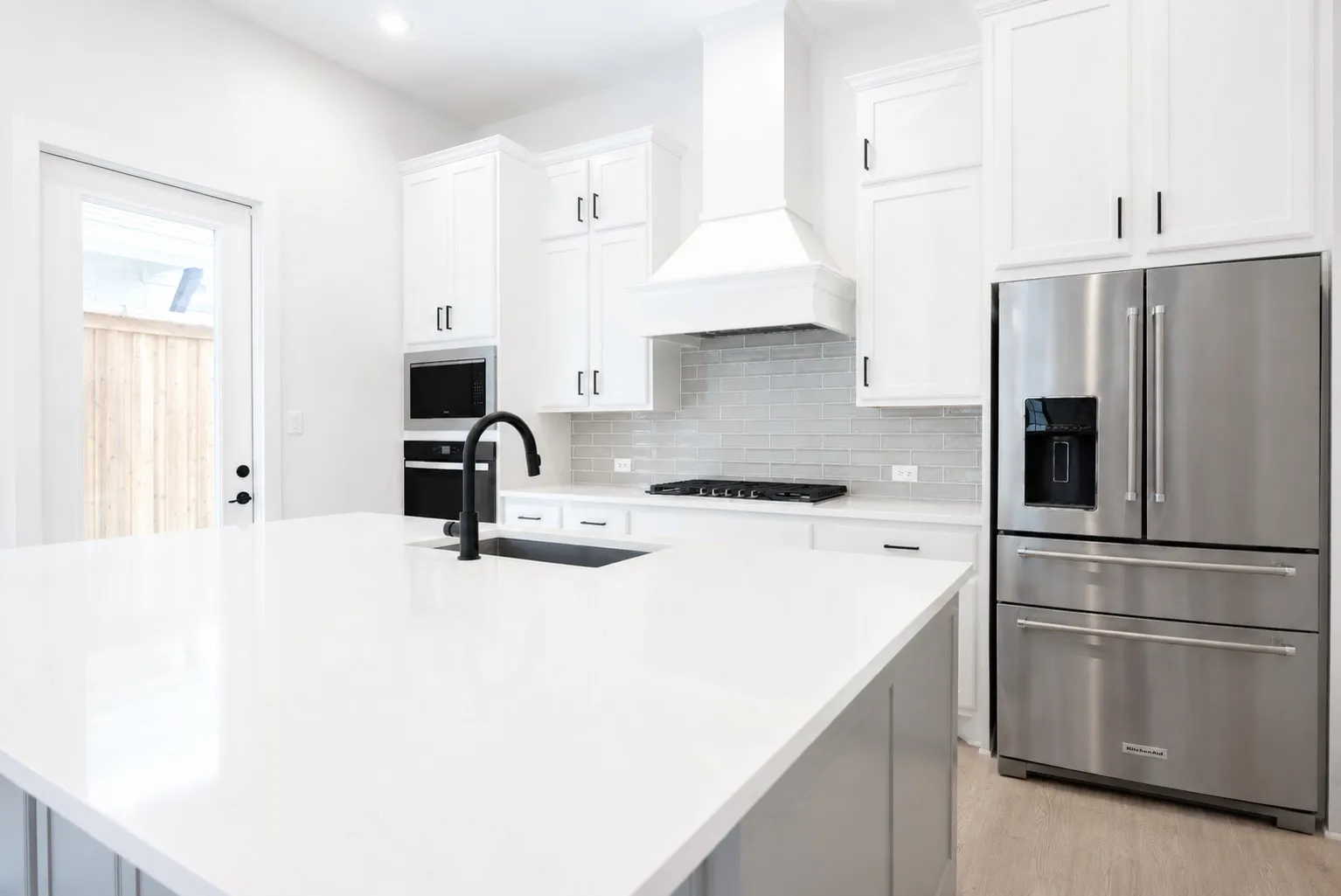 Kitchen island featuring a white countertop with an undermount sink and matte black faucet