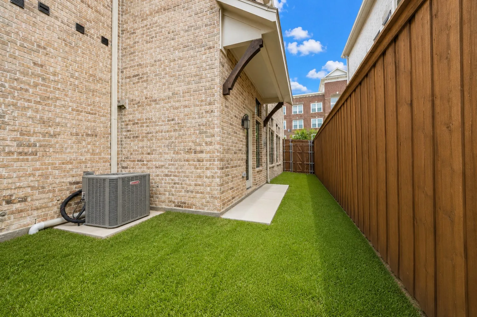 Private outdoor space featuring artificial turf, a wood privacy fence, and a concrete patio
