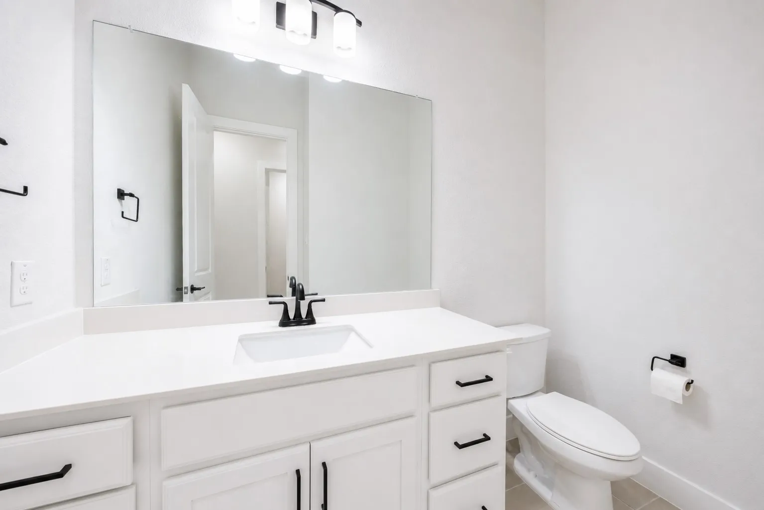 Bathroom featuring a white vanity with an undermount sink, a white countertop, and black hardware