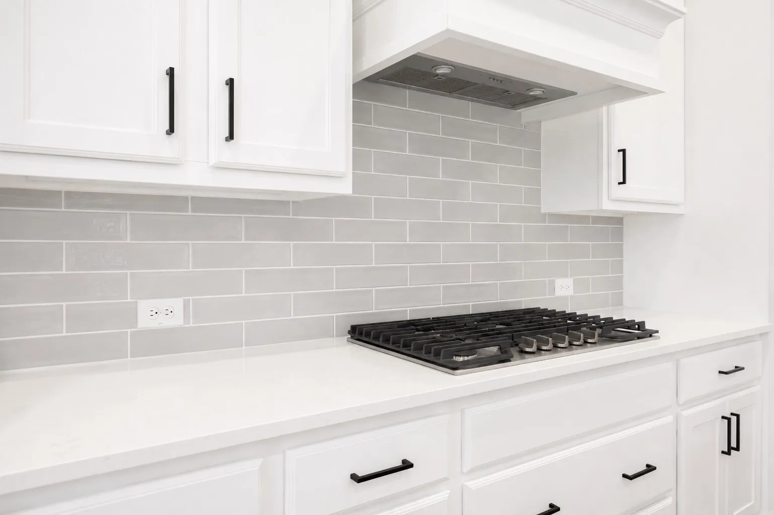 Kitchen featuring a gas cooktop, light grey subway tile backsplash, white shaker-style cabinetry, white countertops, and matte black hardware