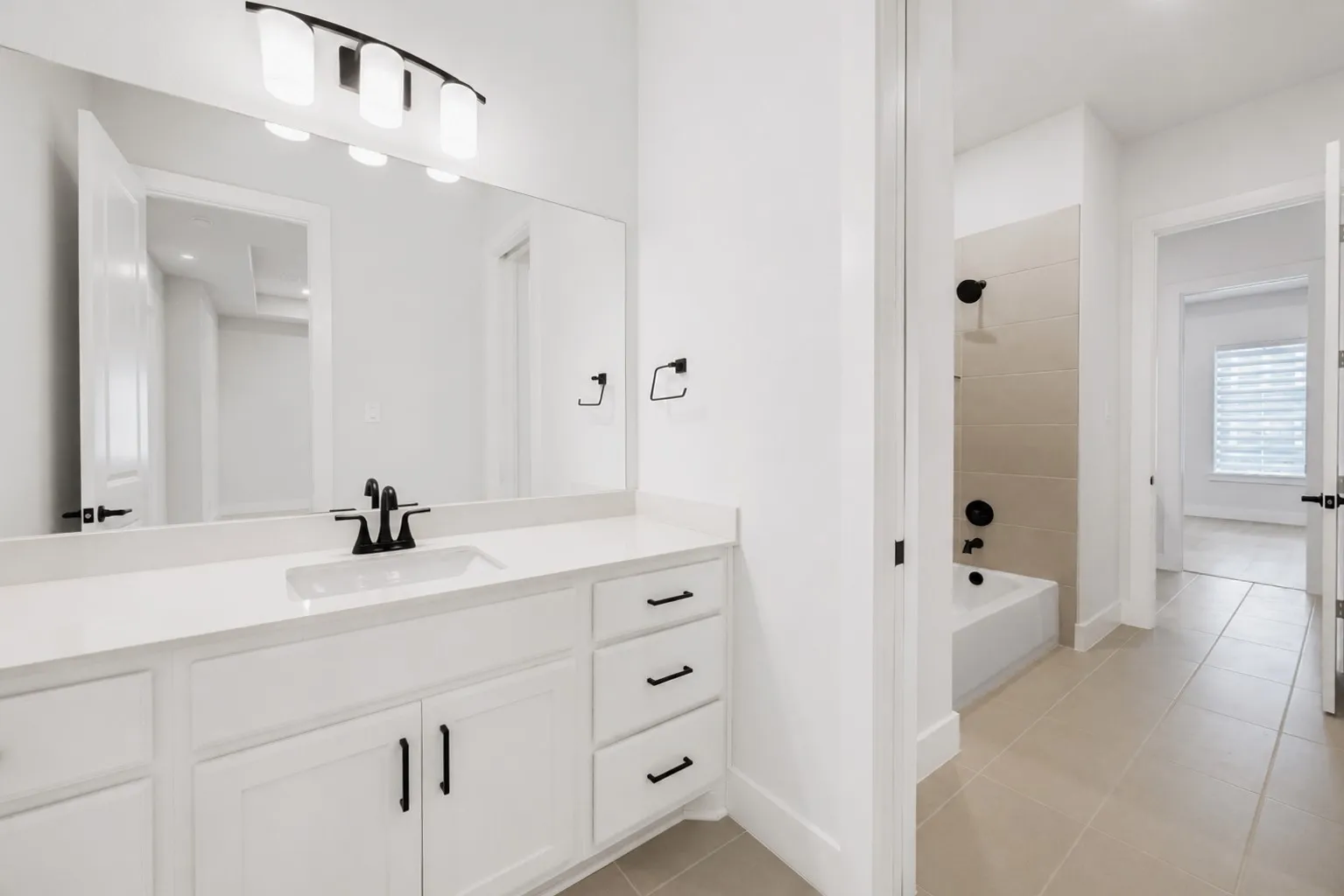 Bathroom featuring a white vanity with an integrated sink, quartz countertop, and matte black fixtures