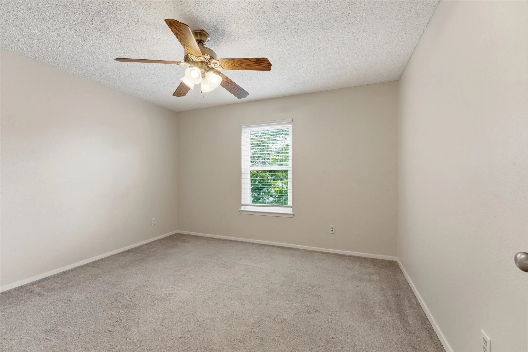 Neutral-toned room featuring a single window with horizontal blinds, providing natural illumination