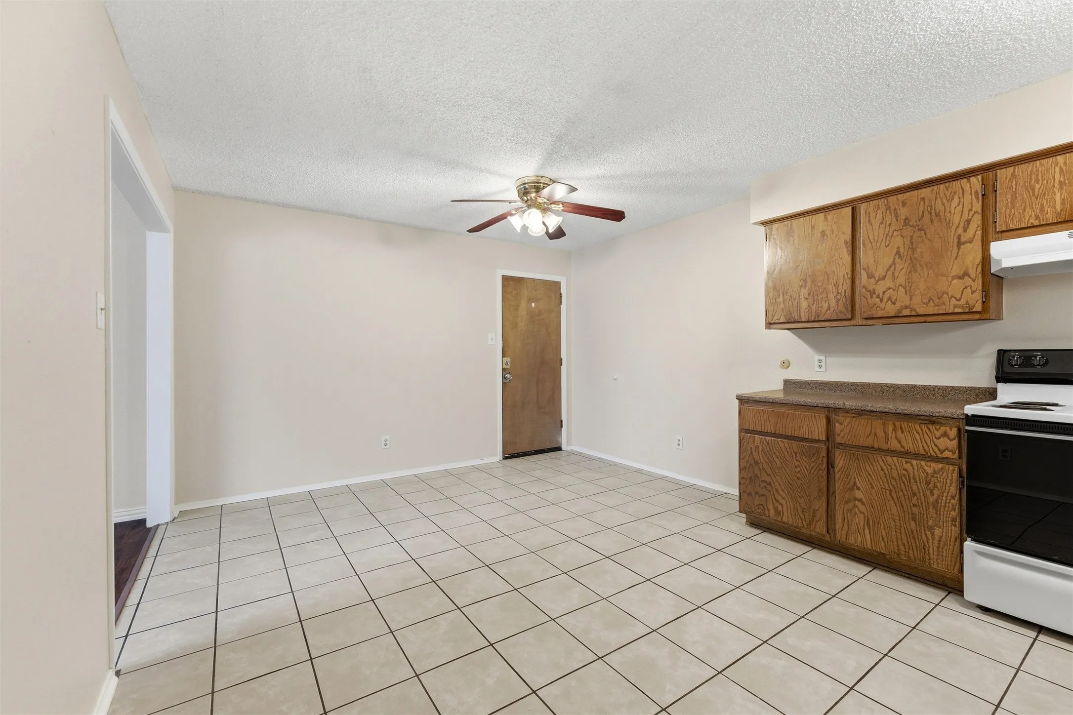 Open-concept living space featuring light-colored tile flooring, a wood-finish ceiling fan, and neutral wall paint