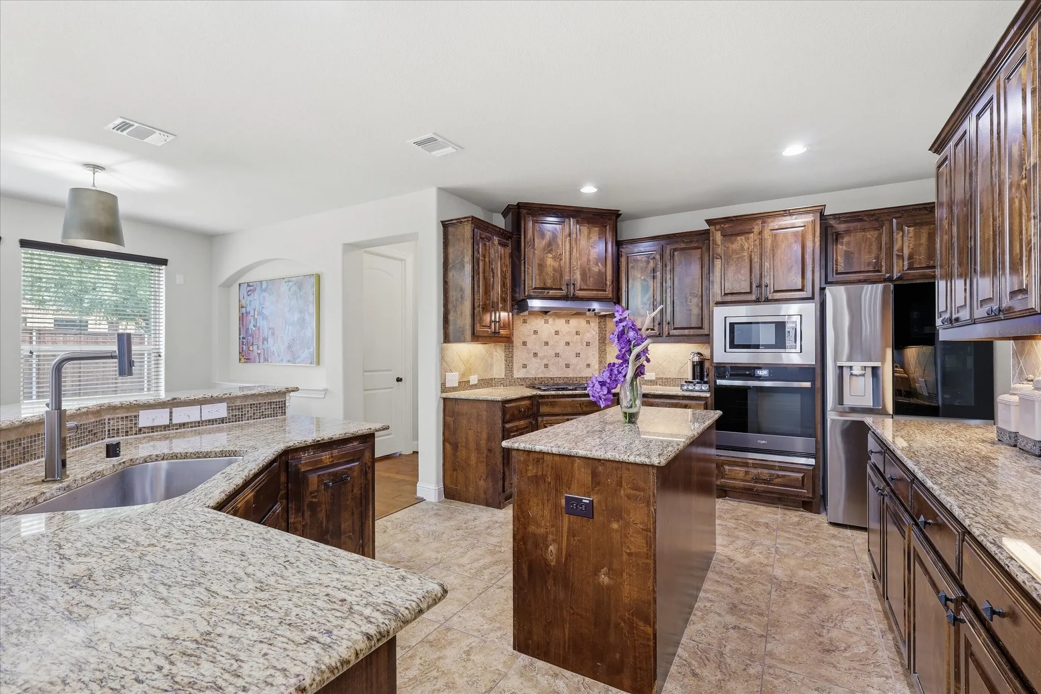 Kitchen Gourmet kitchen featuring rich stained cabinetry, granite countertops, and a decorative tile backsplash.