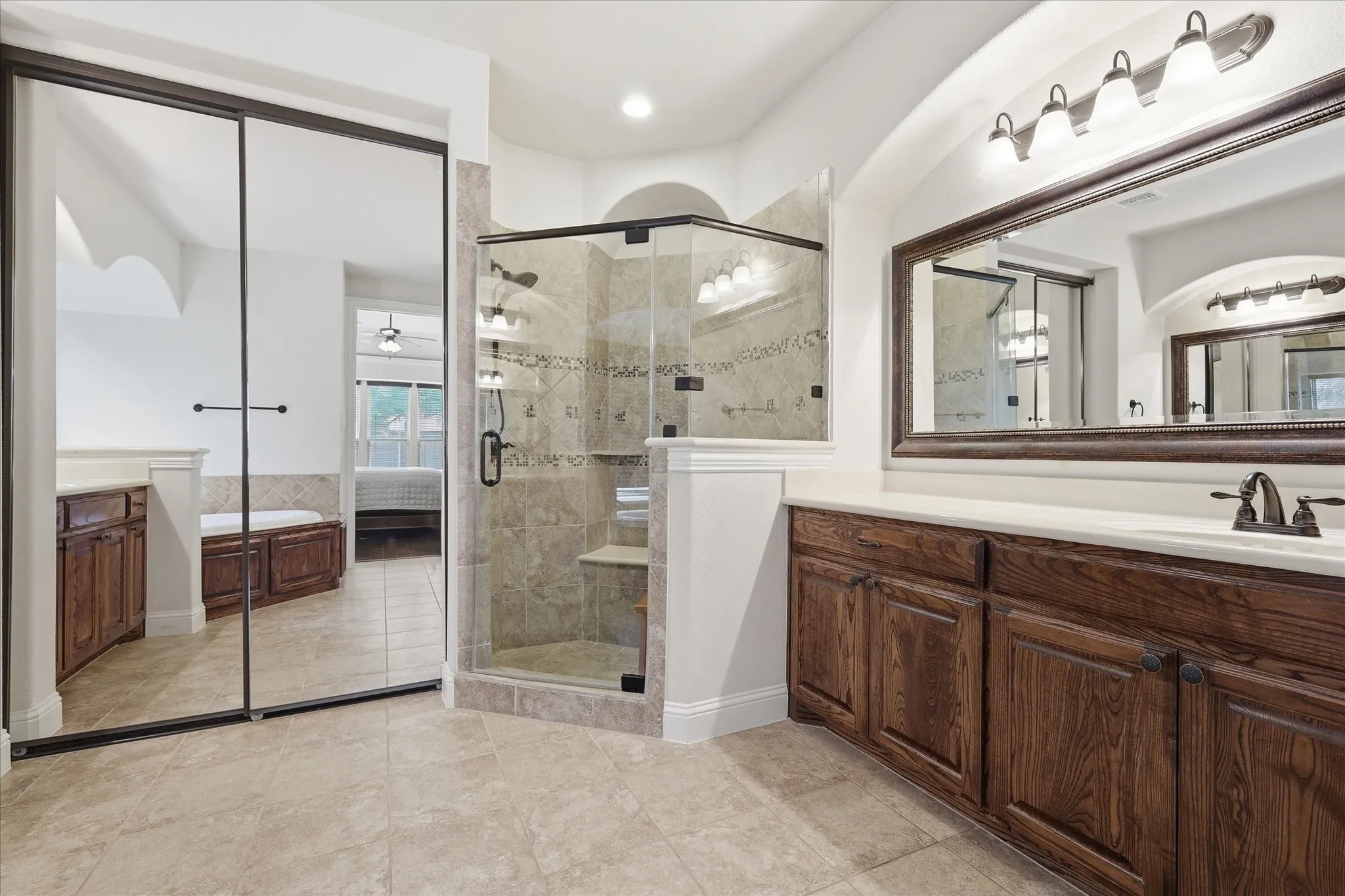 Luxurious spa-like primary bath featuring a glass-enclosed walk-in shower with tile surround and dual showerheads.
