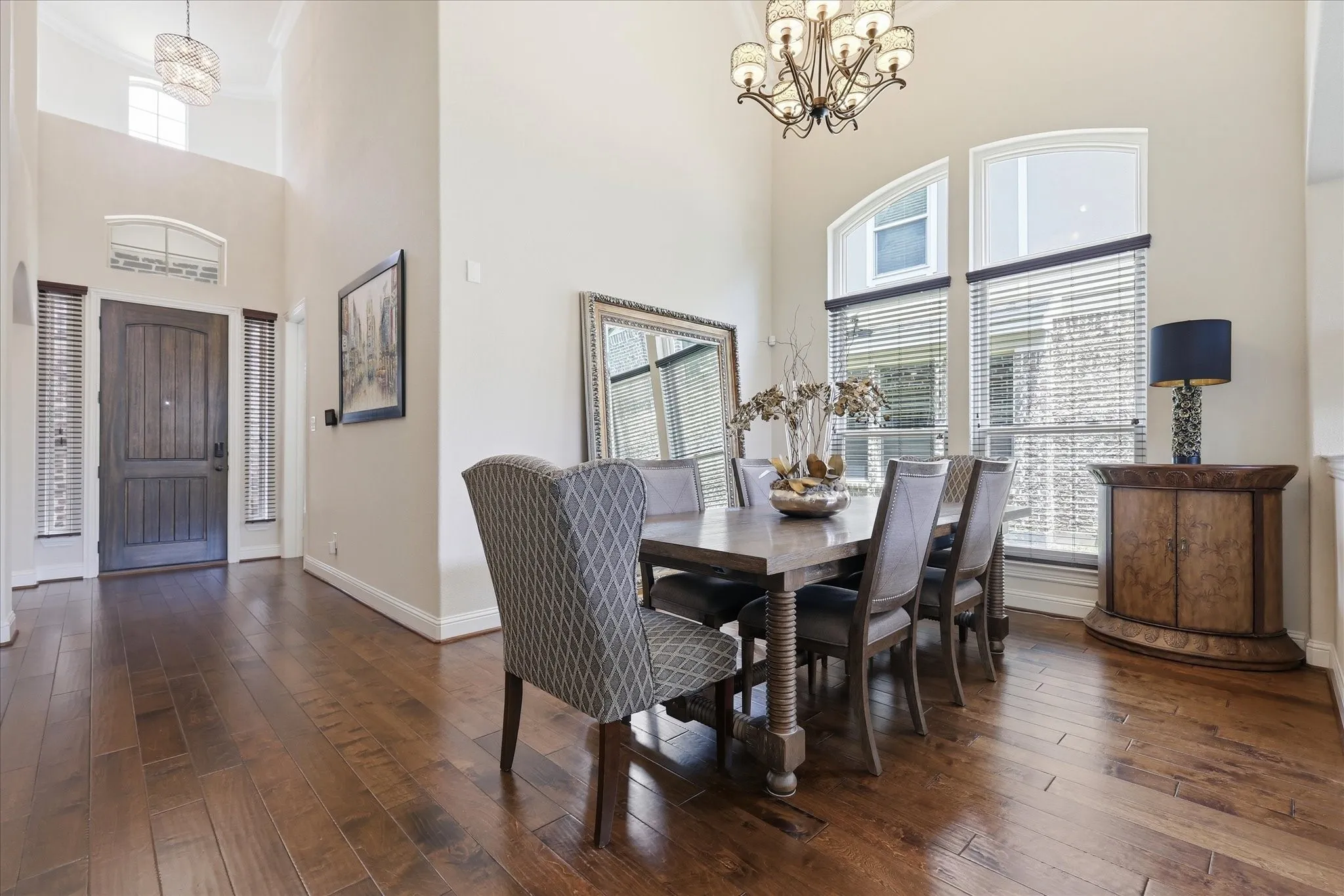 Elegant formal dining space featuring soaring ceilings and an open sightline to the living room and kitchen area.