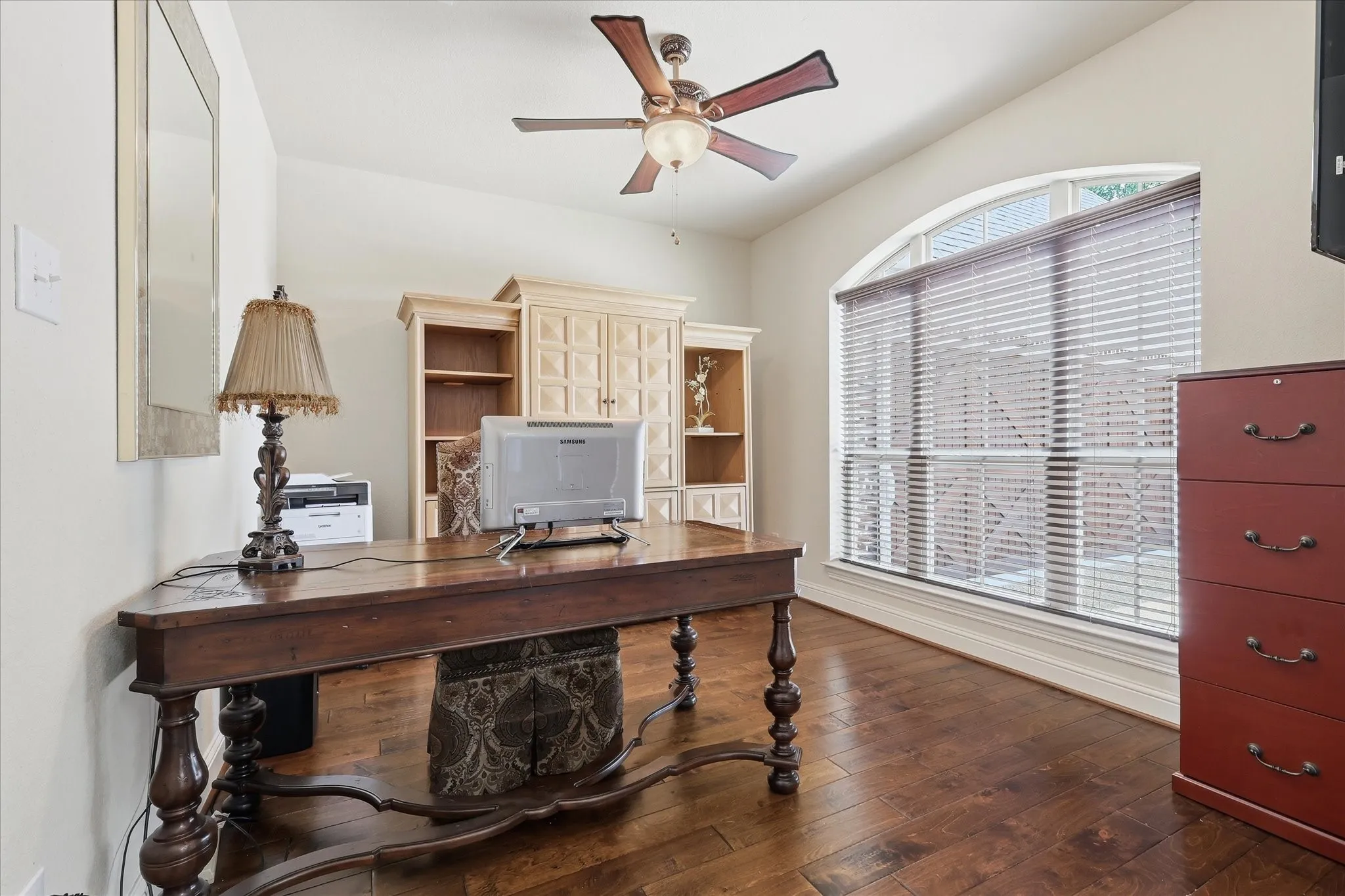 Bright and spacious home office featuring an arched picture window overlooking the front of home.