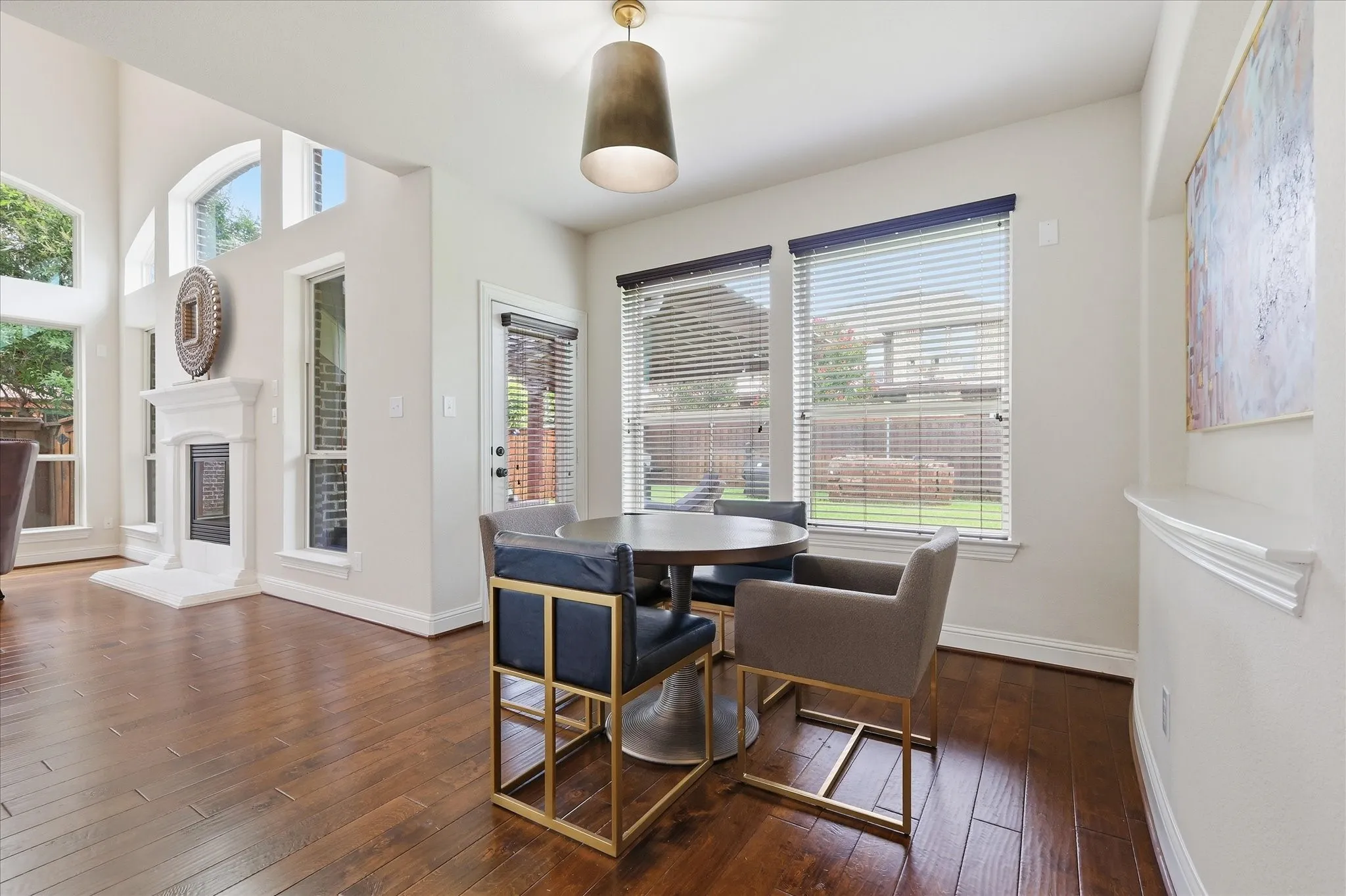 Casual dining space bathed in natural light from a bank of large windows overlooking the backyard.