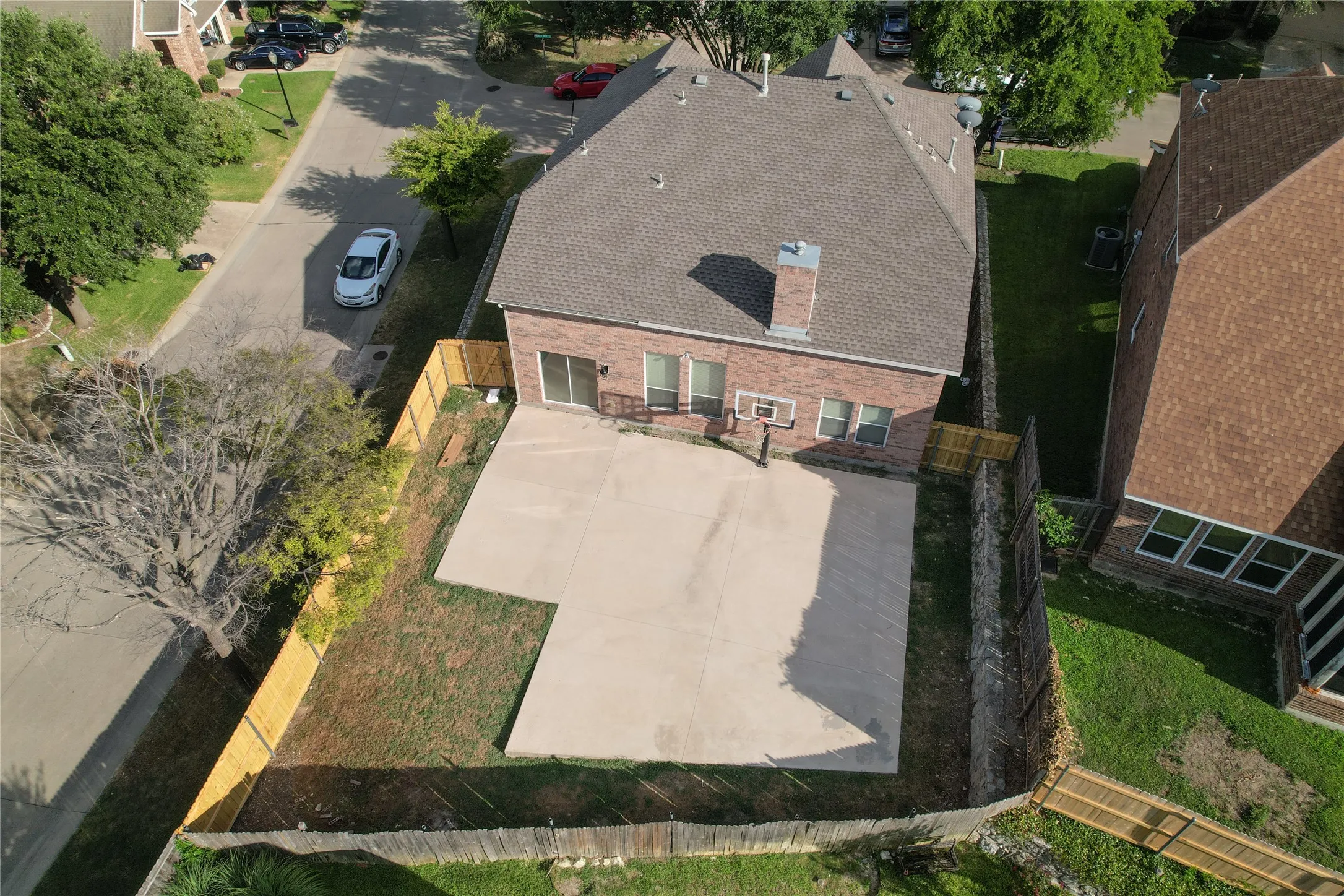 Brick exterior home with a shingled roof, featuring a substantial concrete patio area