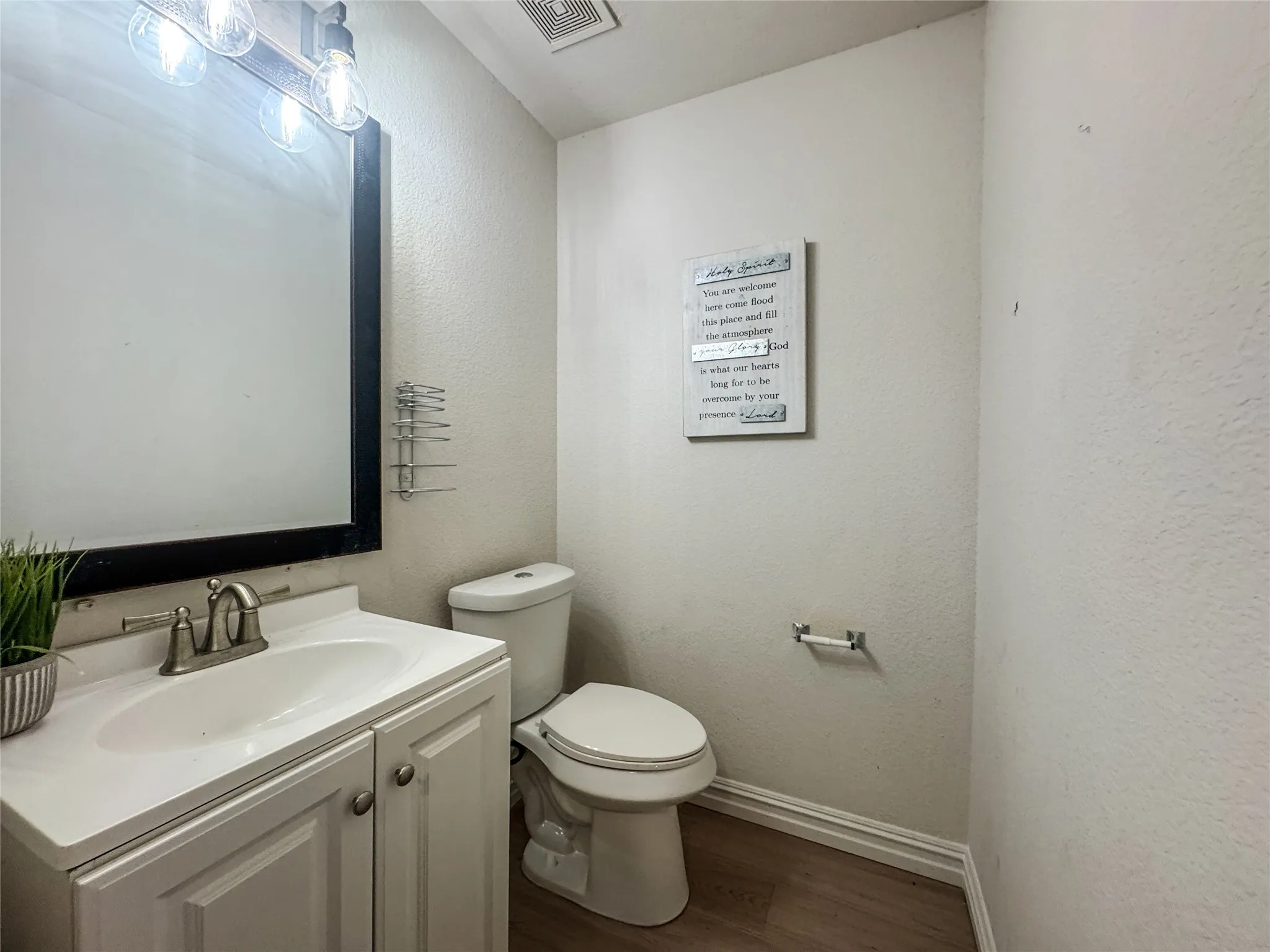 Compact bathroom featuring a white vanity with panel doors and a brushed nickel faucet