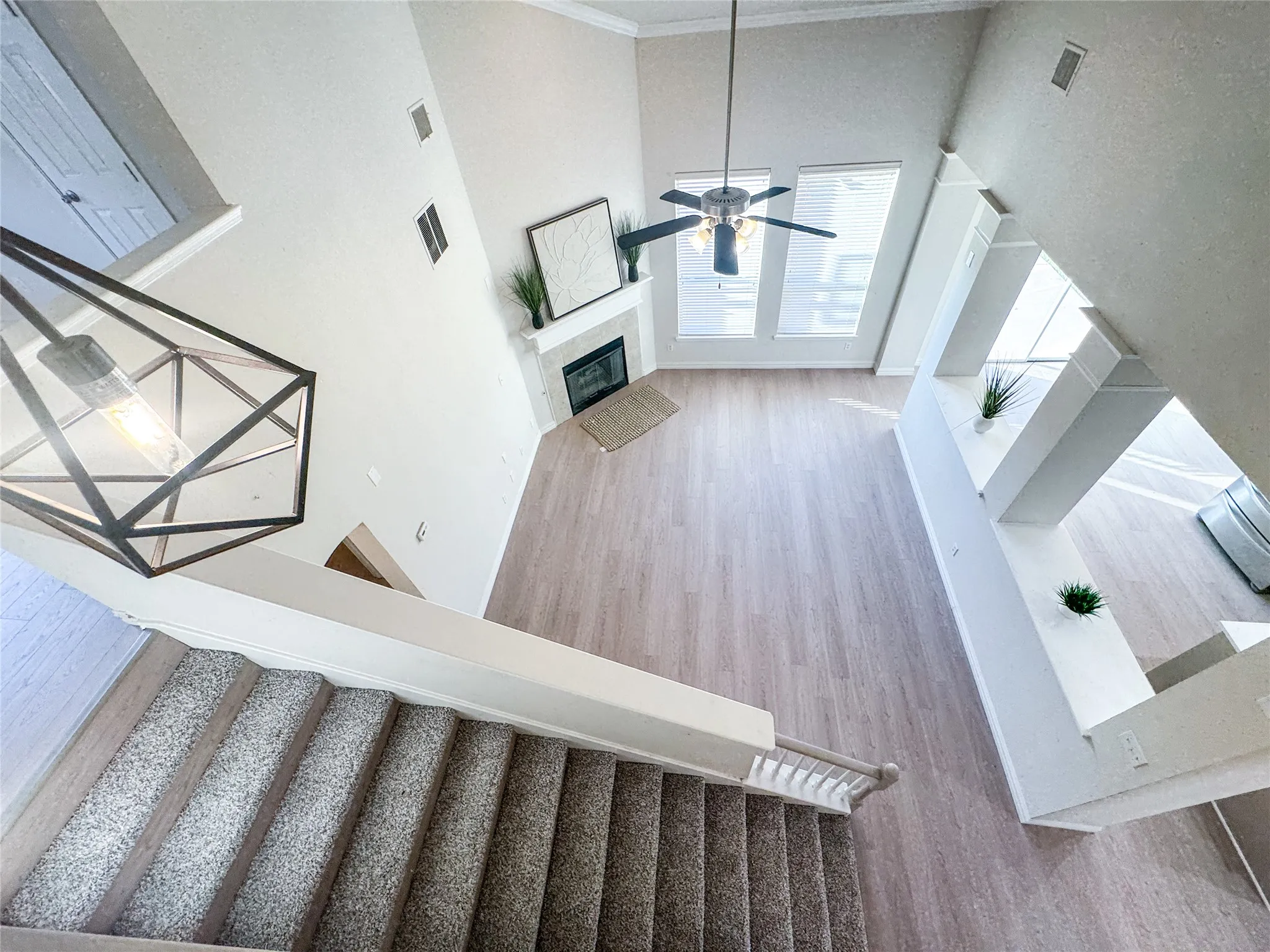 Two-story living area featuring vaulted ceilings, wood-finish flooring, and a fireplace with a mantel