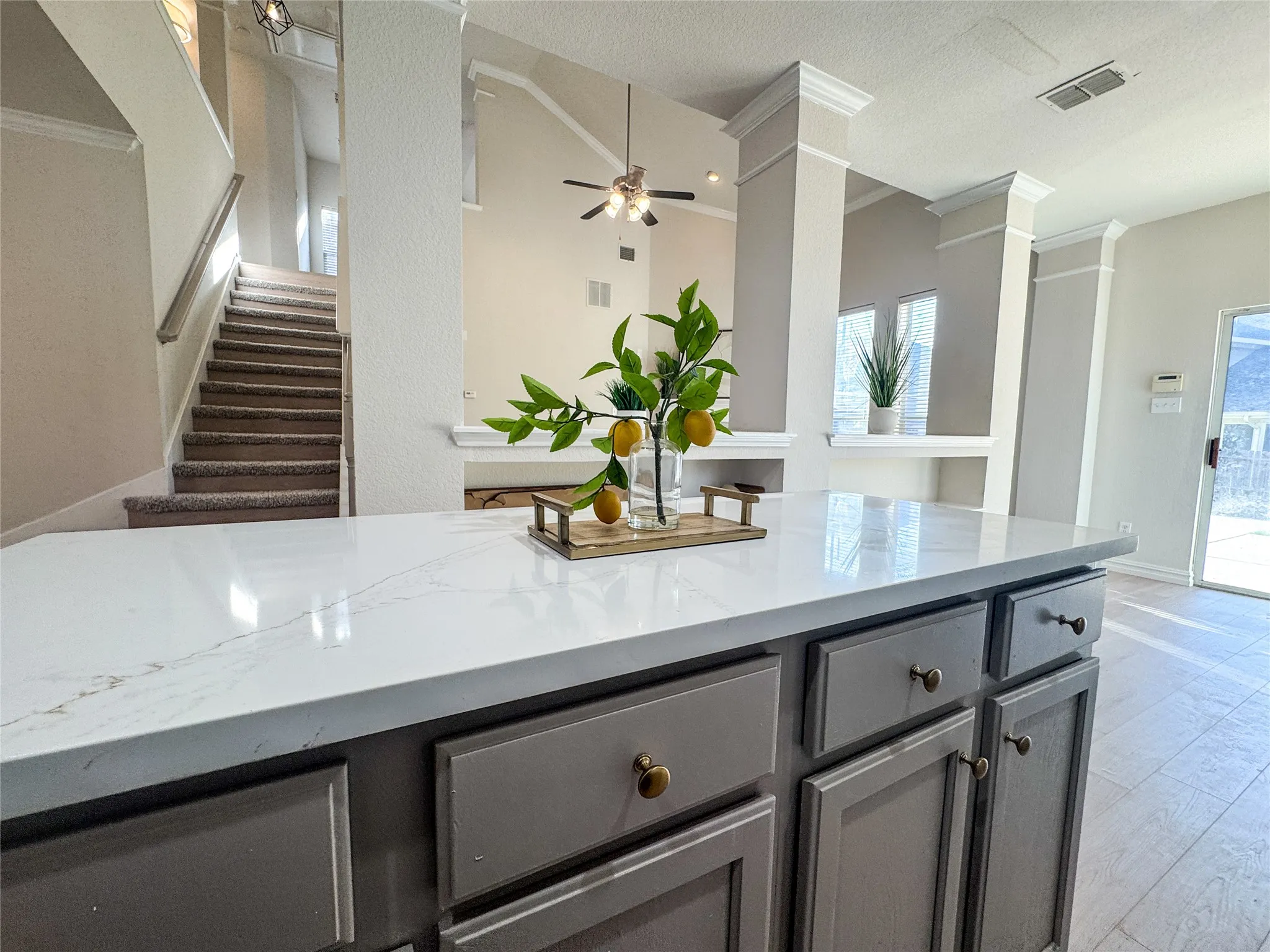Kitchen island featuring a white countertop with subtle veining, gray cabinetry, and brass hardware