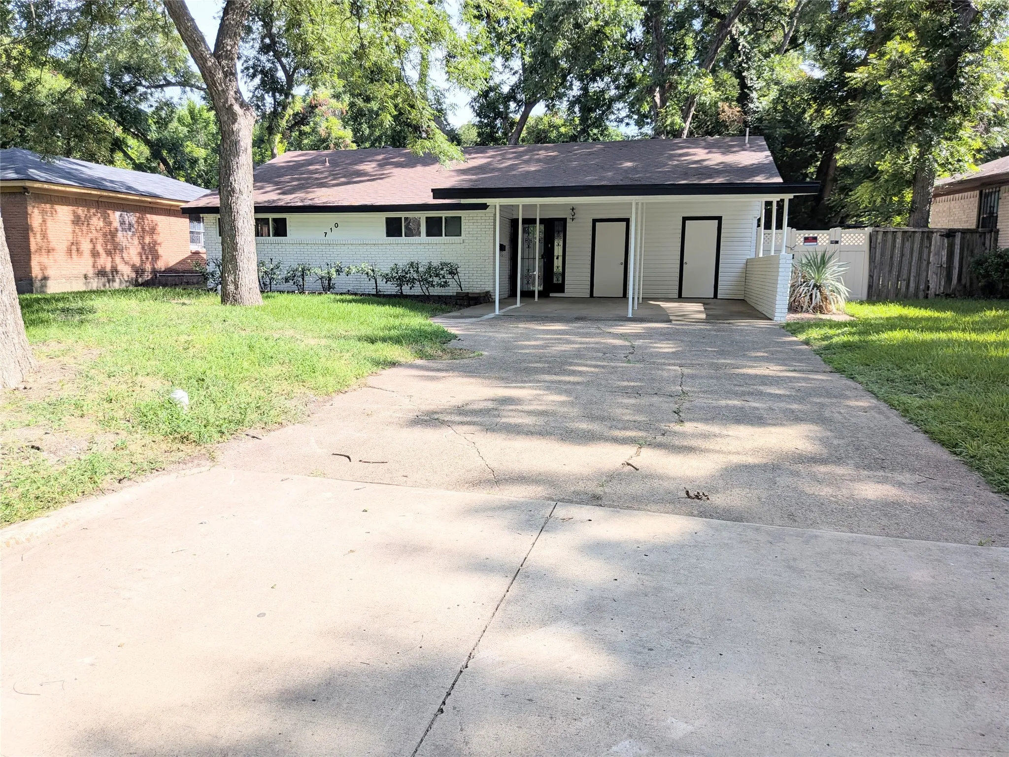 Ranch-style exterior with a dark shingle roof and white siding