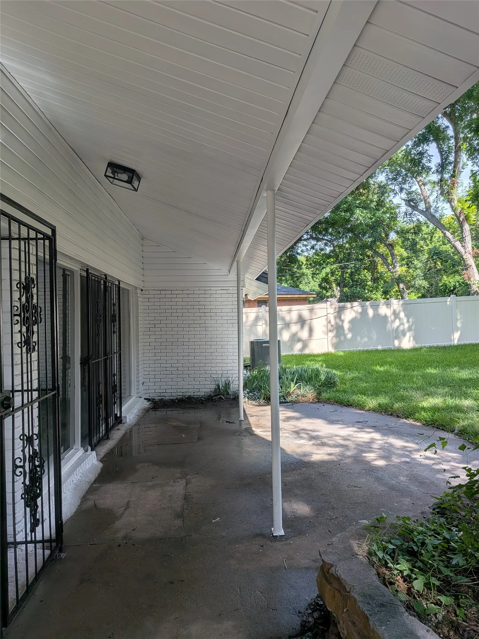 Covered patio area featuring a concrete surface, white brick exterior wall, and white siding soffit