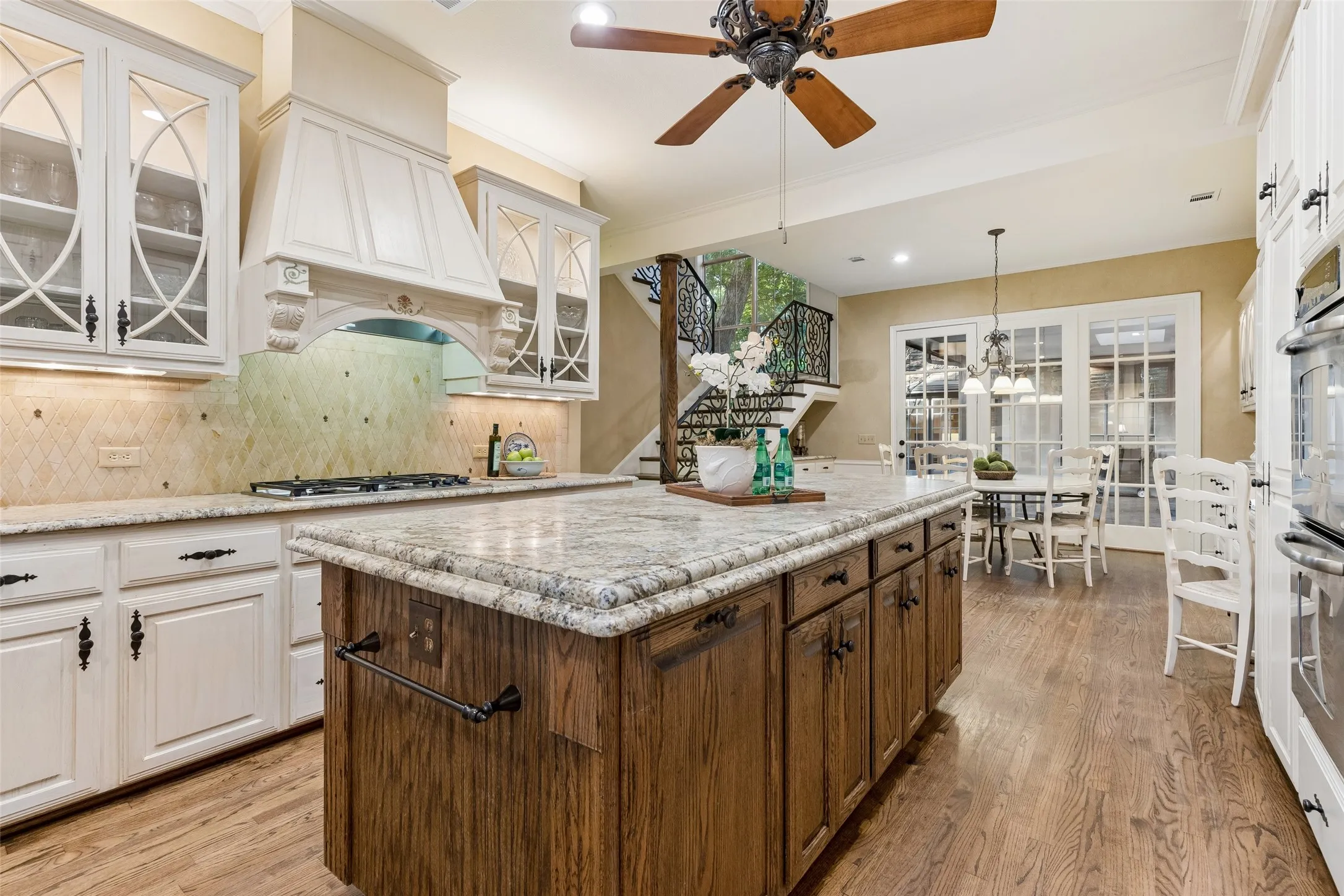 A beautiful Granite topped Island with Waterfall edge and Cabinets with a Country French scroll that include lights   make you want to spend time in the Kitchen. Wait until you see the lights at night!  TWO Pantries! Note beadboard on either end of Island