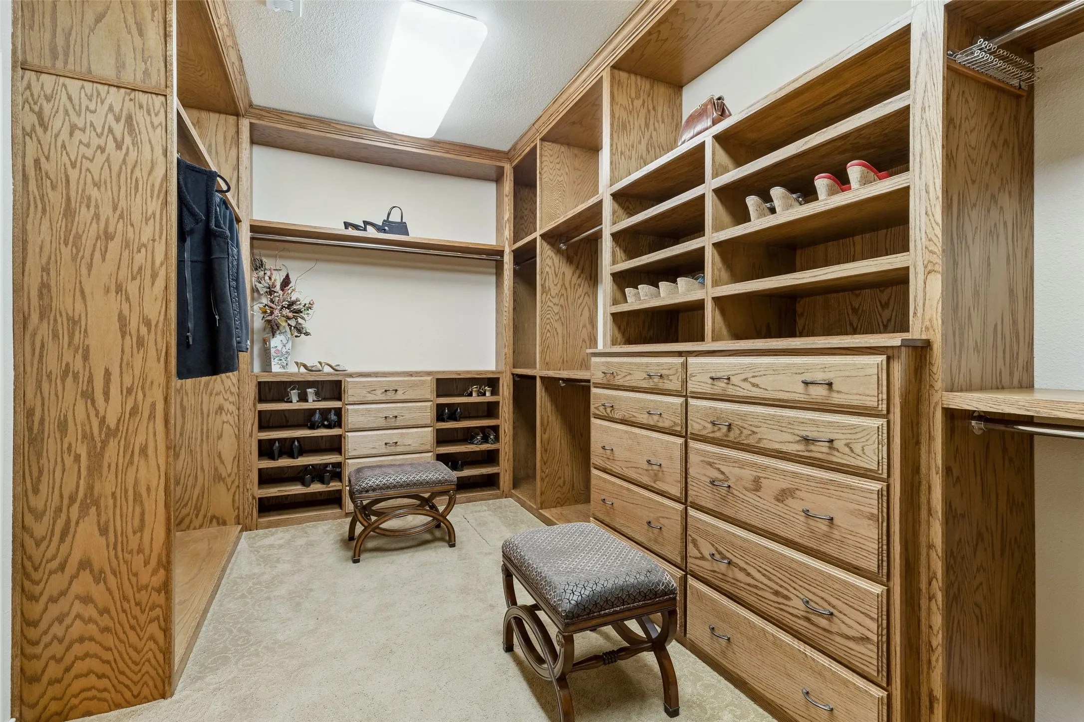 Primary closet has built-in drawers and lots of other storage areas for you to put your personal belongings.  Large dressing area with carpeted flooring.