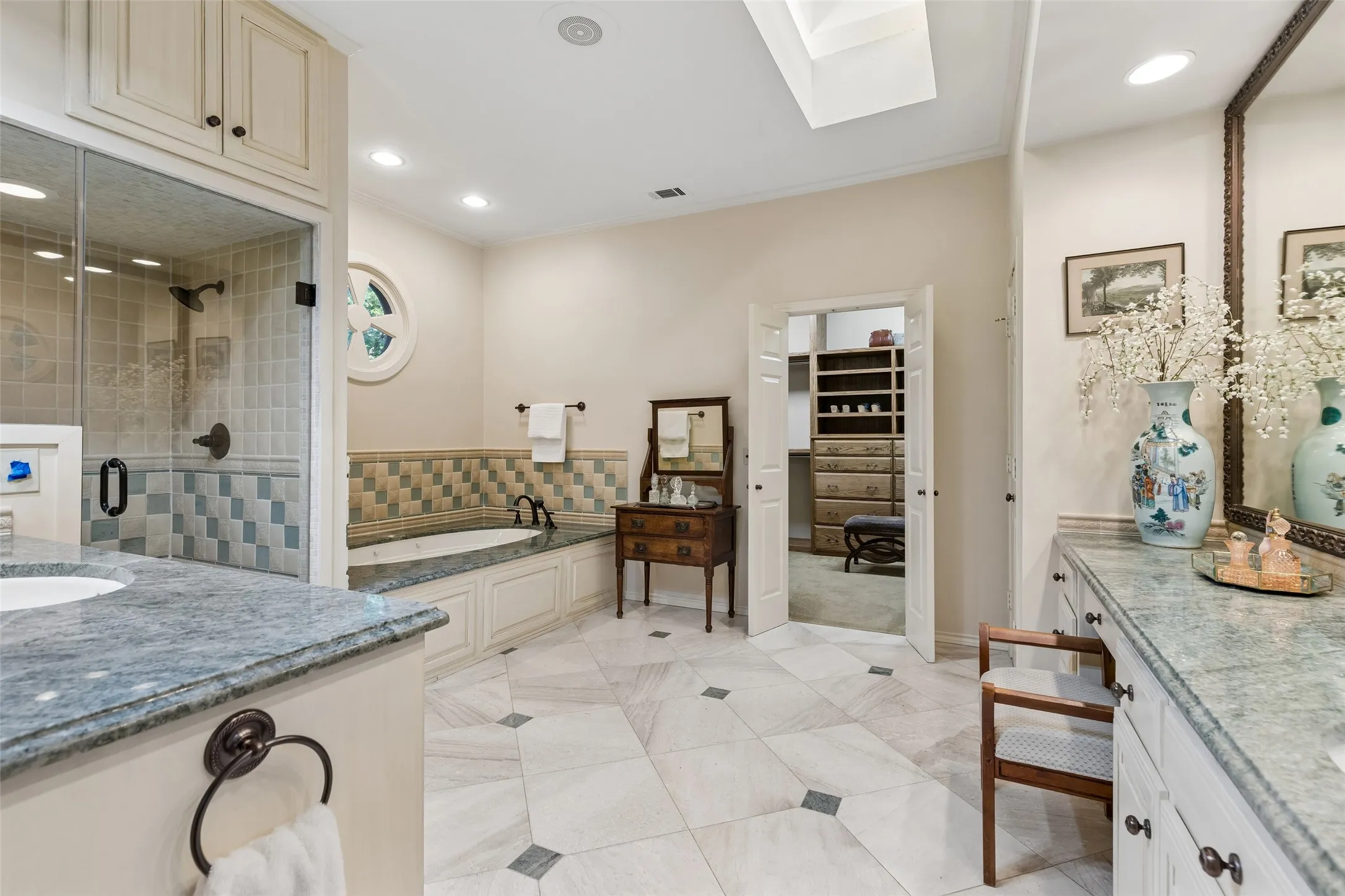 Primary bath has dual vanities, recessed lighting plus a skylight, easy care tile flooring, soaking garden tub and lots of storage space!