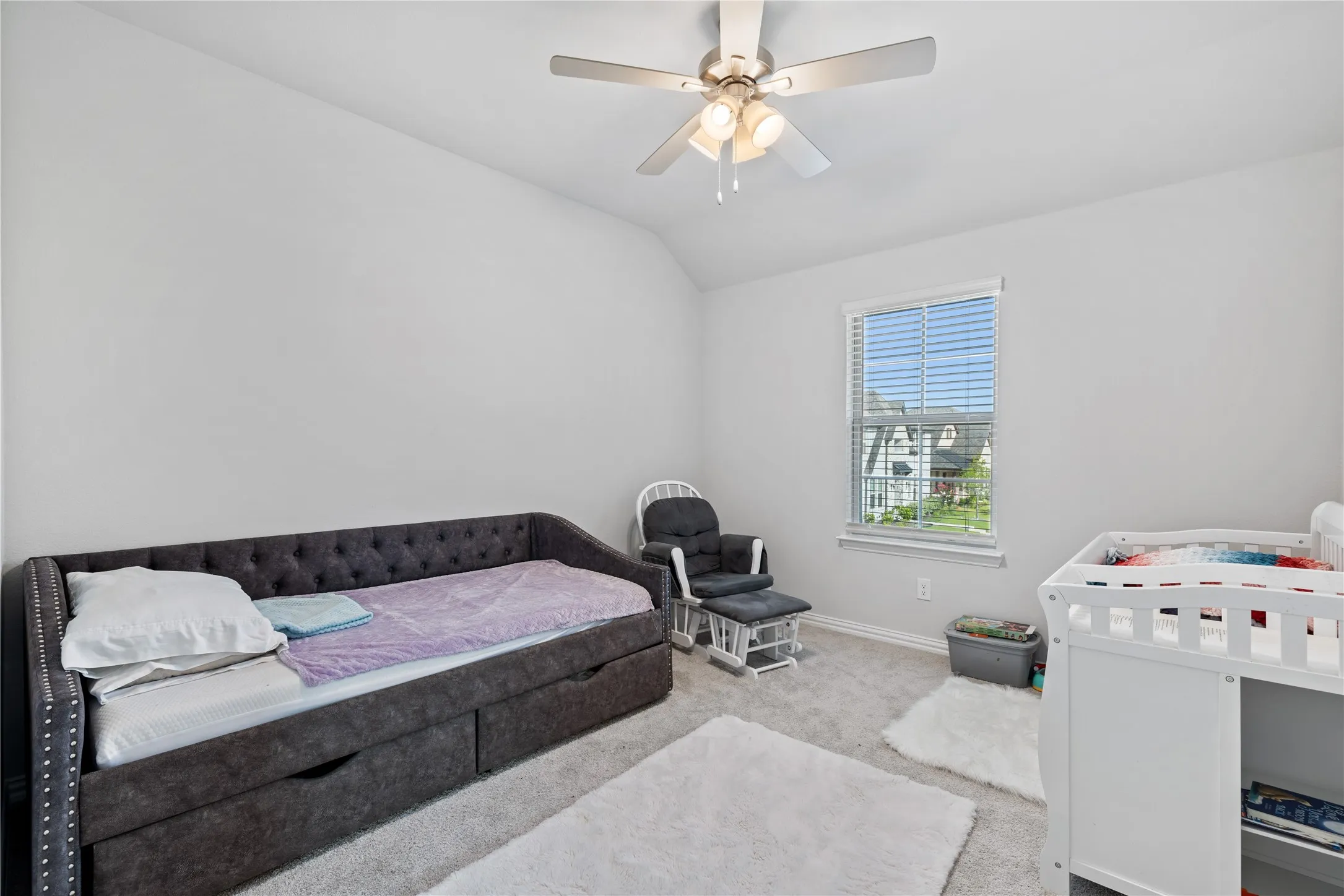 Versatile secondary bedroom with soaring ceilings, oversized window, plush carpeting, and flexible space ideal for a nursery, children’s bedroom, guest room, or home office.