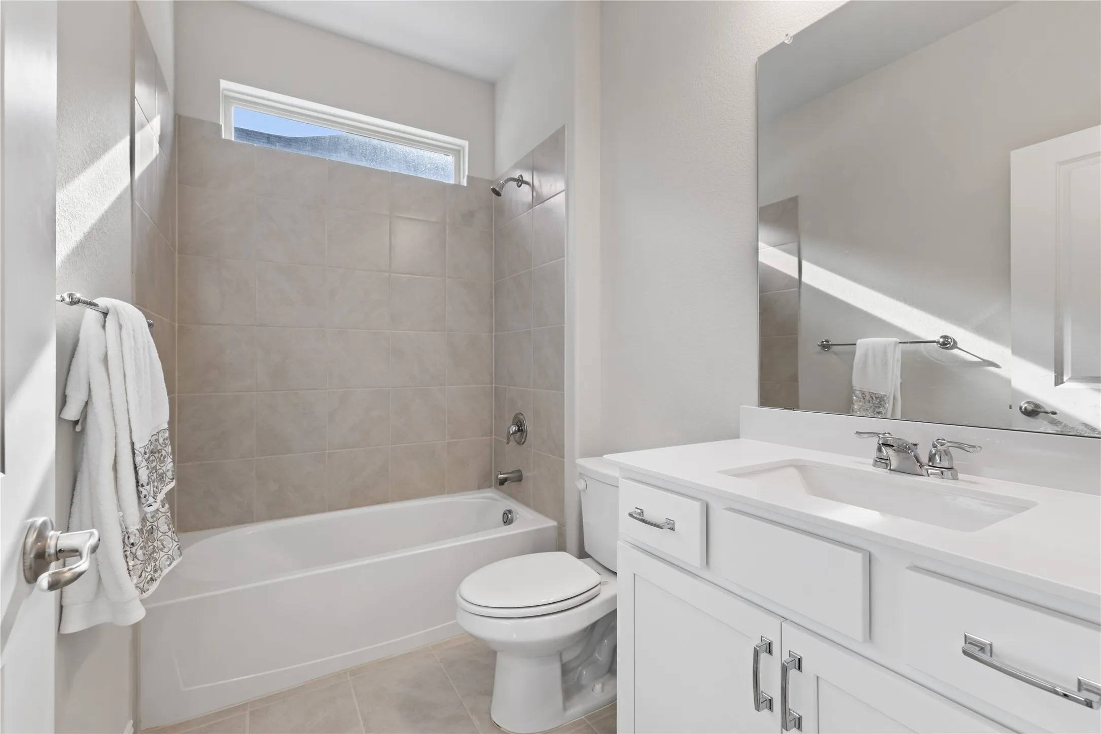 Designer full bathroom featuring upgraded cabinetry, quartz vanity, oversized mirror, tiled tub/shower combination, and modern finishes ideal for guests or downstairs living.