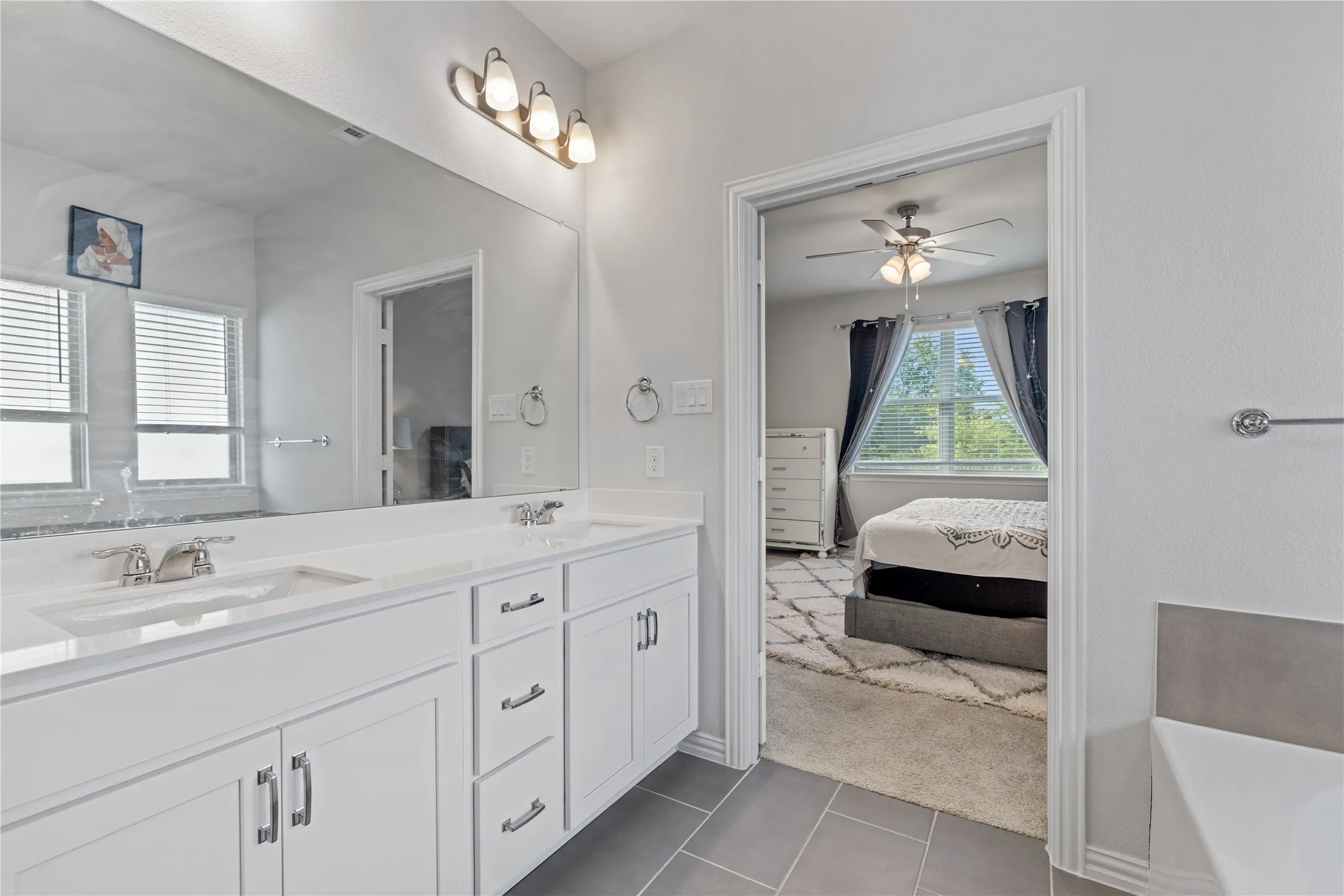 Elegant owner’s bath with expansive dual sink vanity, abundant cabinet storage, modern finishes, and direct access to the spacious walk-in closet and primary suite.