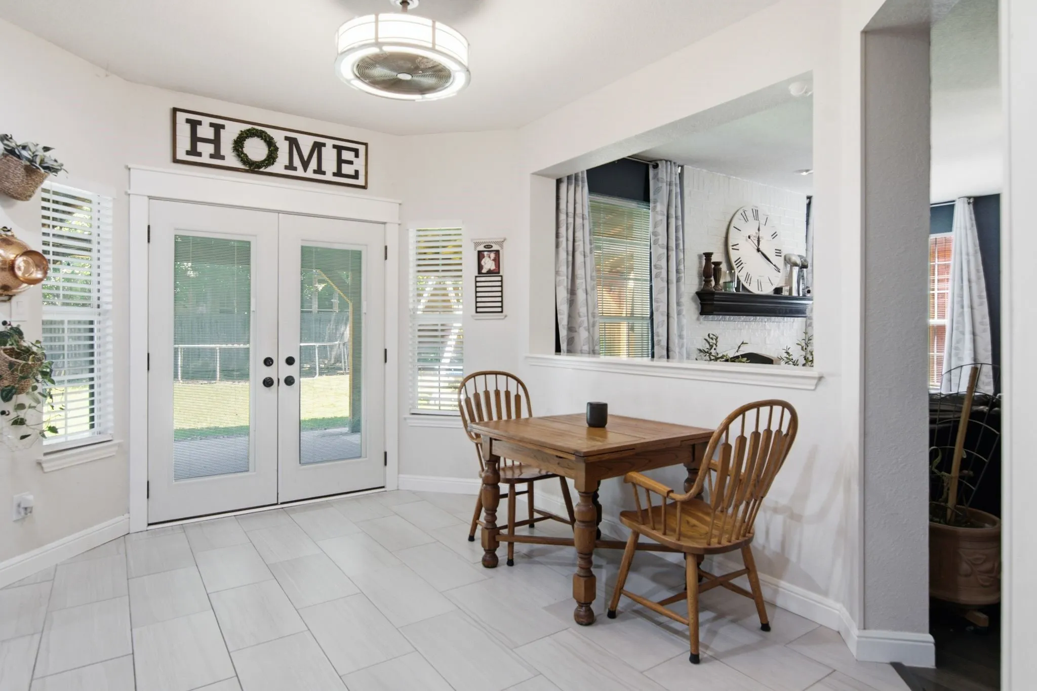 White French doors with clear glass panes open to the exterior, flanked by two windows with white blinds