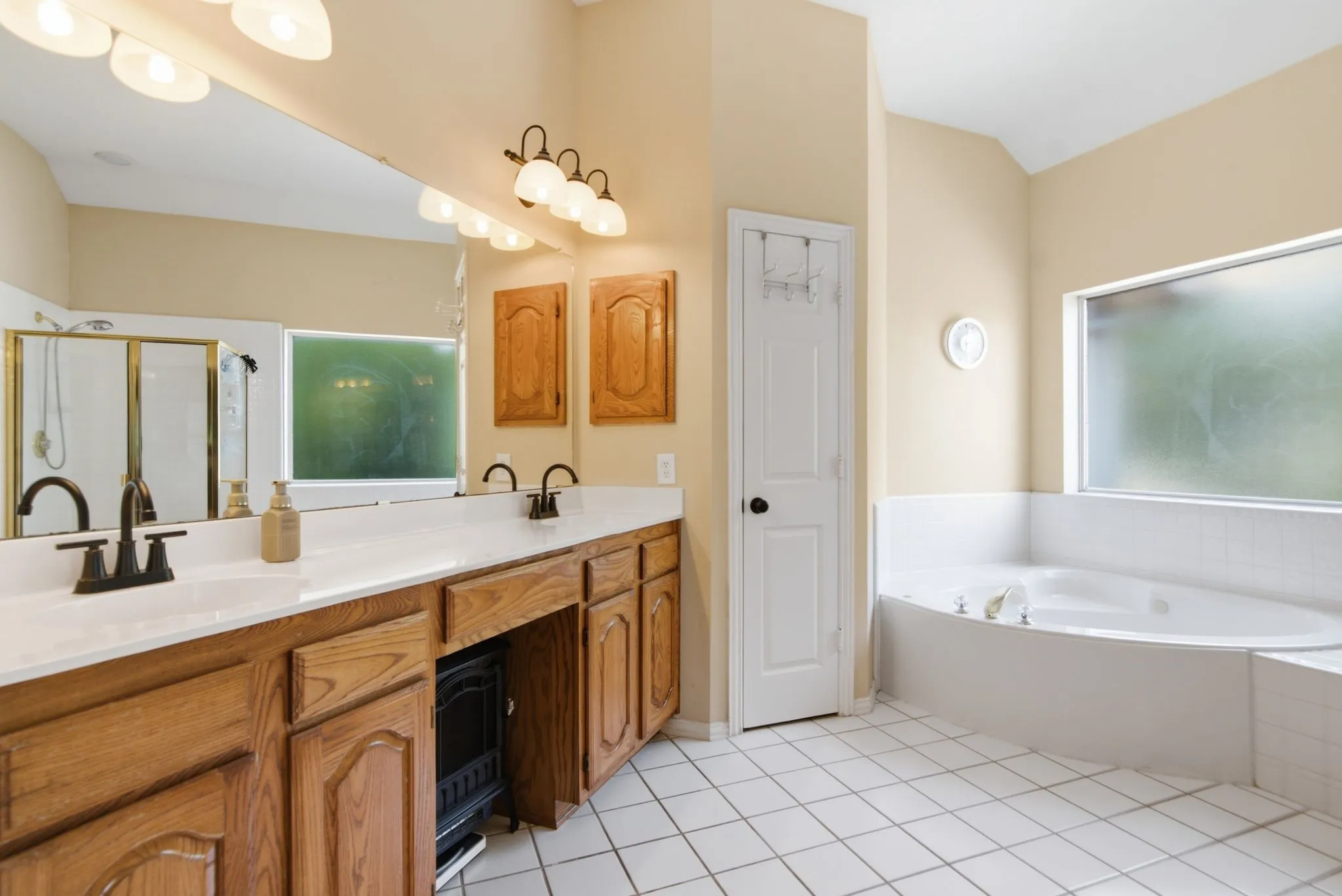 Bathroom featuring a dual vanity with wood cabinetry, linen closet and medicine cabinet.