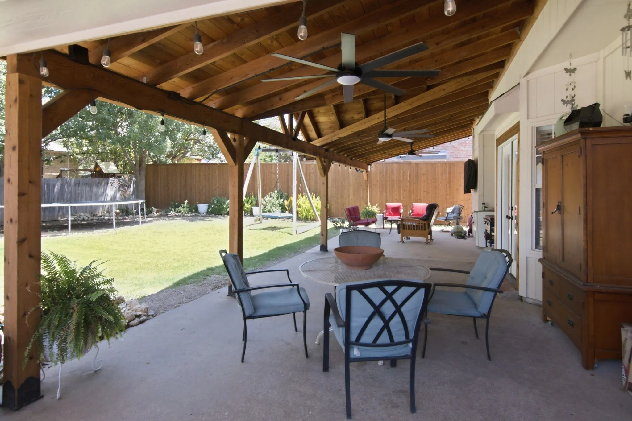 Spacious covered patio with a pitched wood beam ceiling, several ceiling fans, and easy access to the backyard.