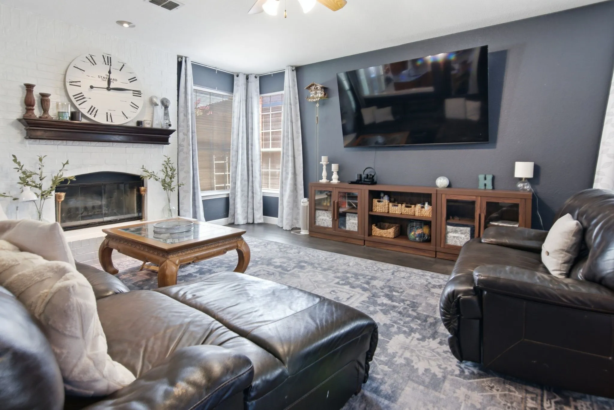 A cozy family room with a whitewashed brick fireplace topped by a dark wood mantel.