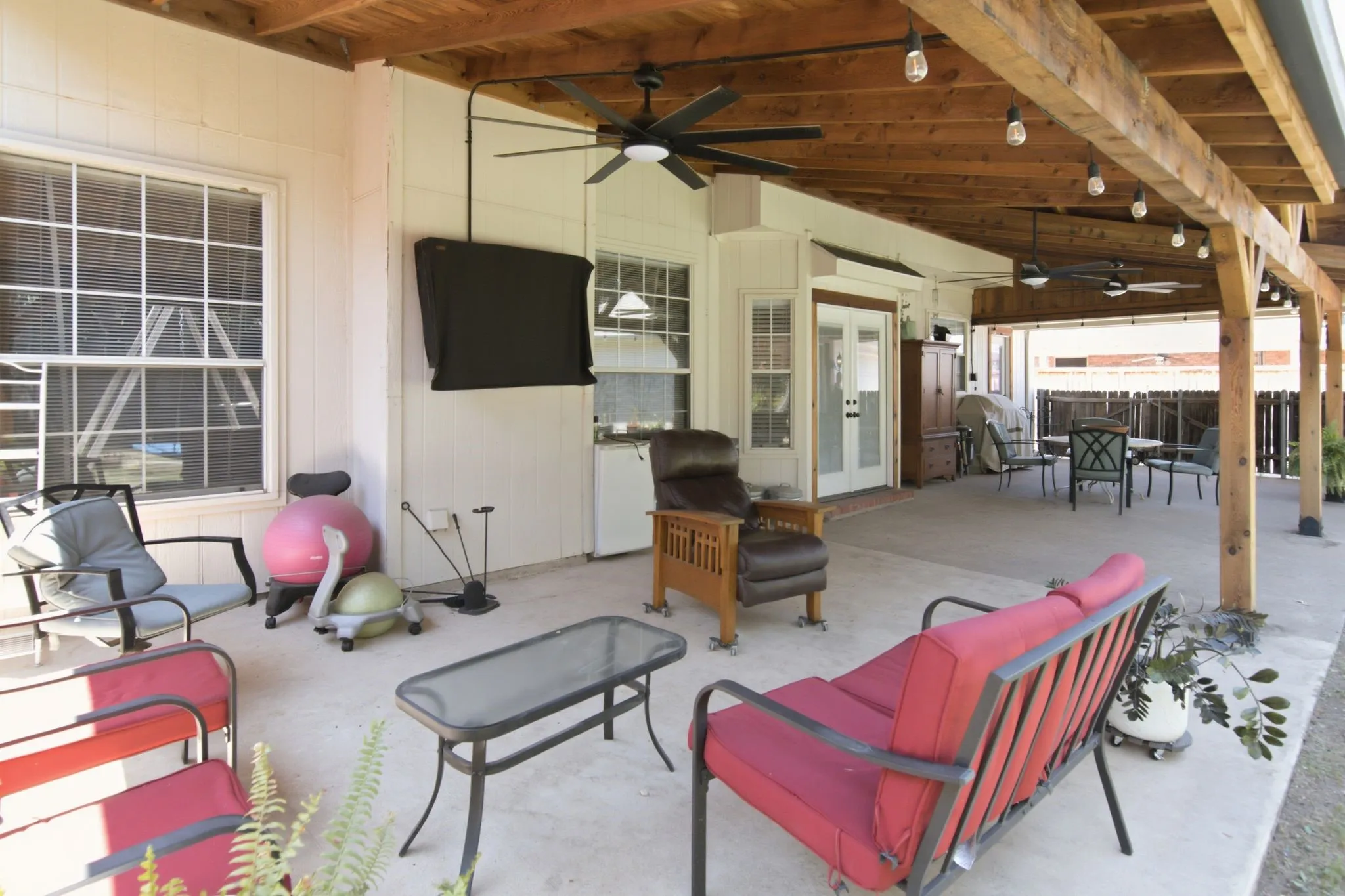 Spacious covered patio with a wood-beam ceiling, several ceiling fans, recessed lighting, and a sturdy concrete patio.