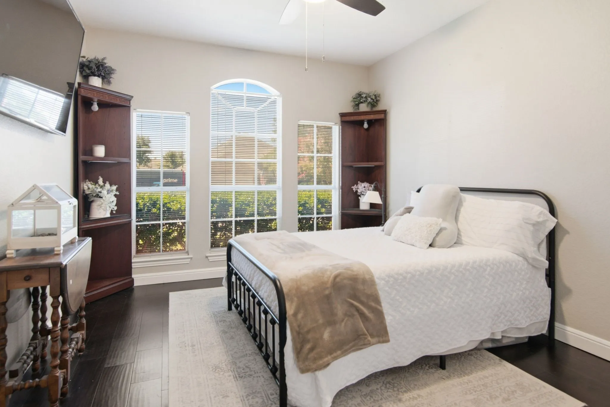Bedroom downstairs, ceiling fan, dark wood-finish flooring, and multiple windows including an arched top window, oversize closet.