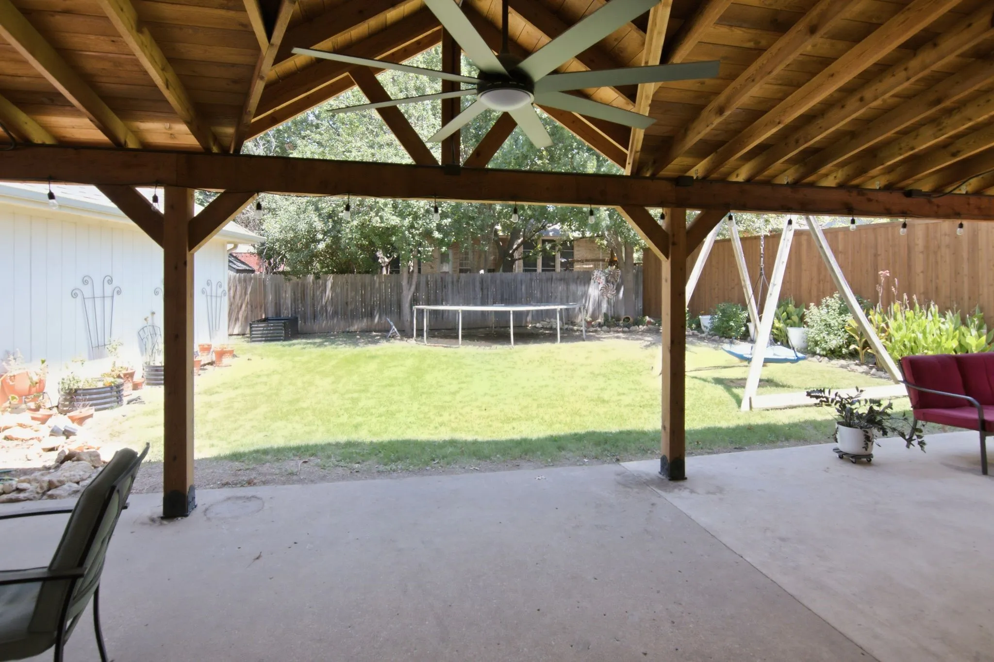 Expansive covered patio with a natural wood ceiling and exposed beams, ceiling fans, and plenty of space to arrange to suit your lifestyle.
