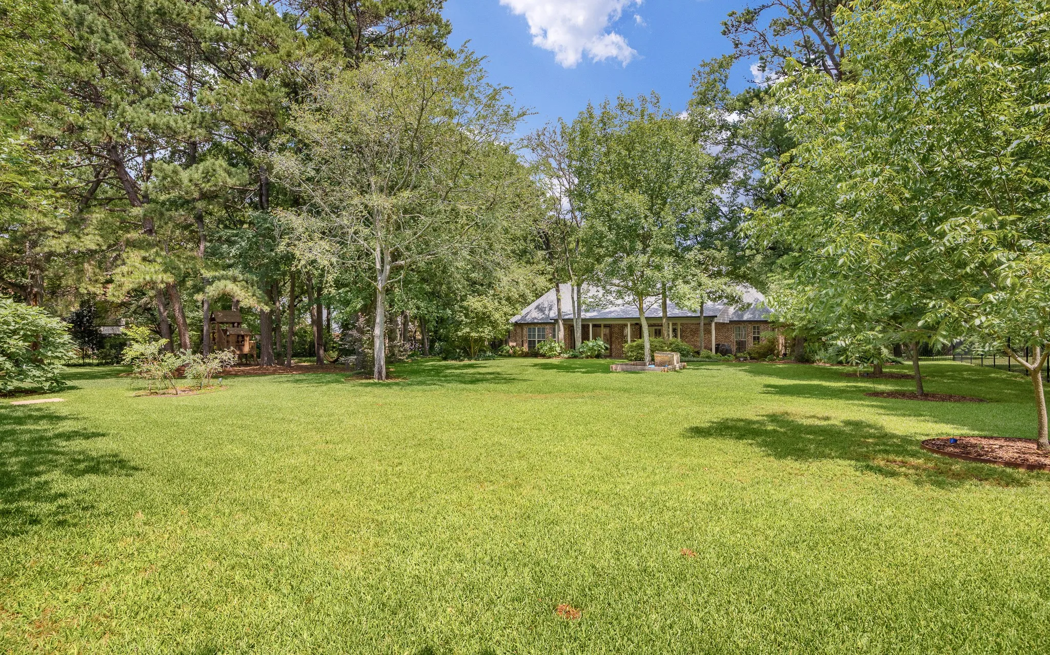Expansive green lawn surrounded by mature trees,