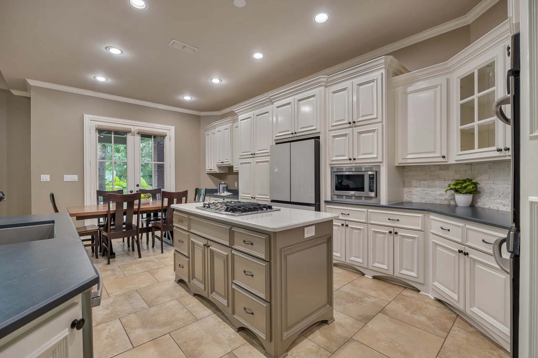 Kitchen featuring a central island with a gas cooktop, perimeter cabinetry with dark countertops, stainless steel appliances including built-in microwave, and tile flooring