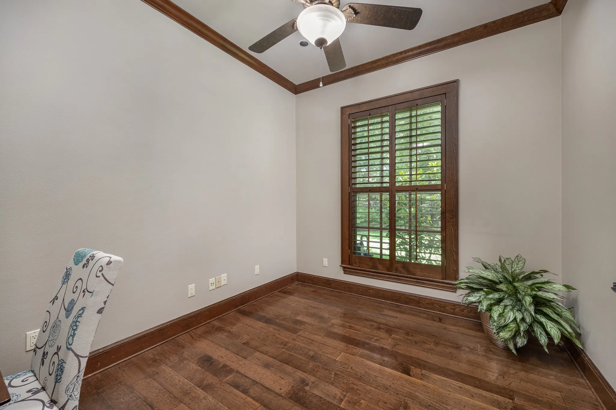 Featuring wood flooring, ceiling fan and window with plantation shutters