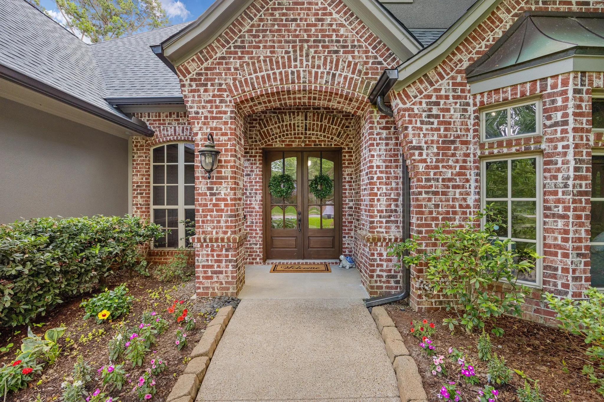 Brick and stucco exterior with an arched entryway and double glass-paneled doors
